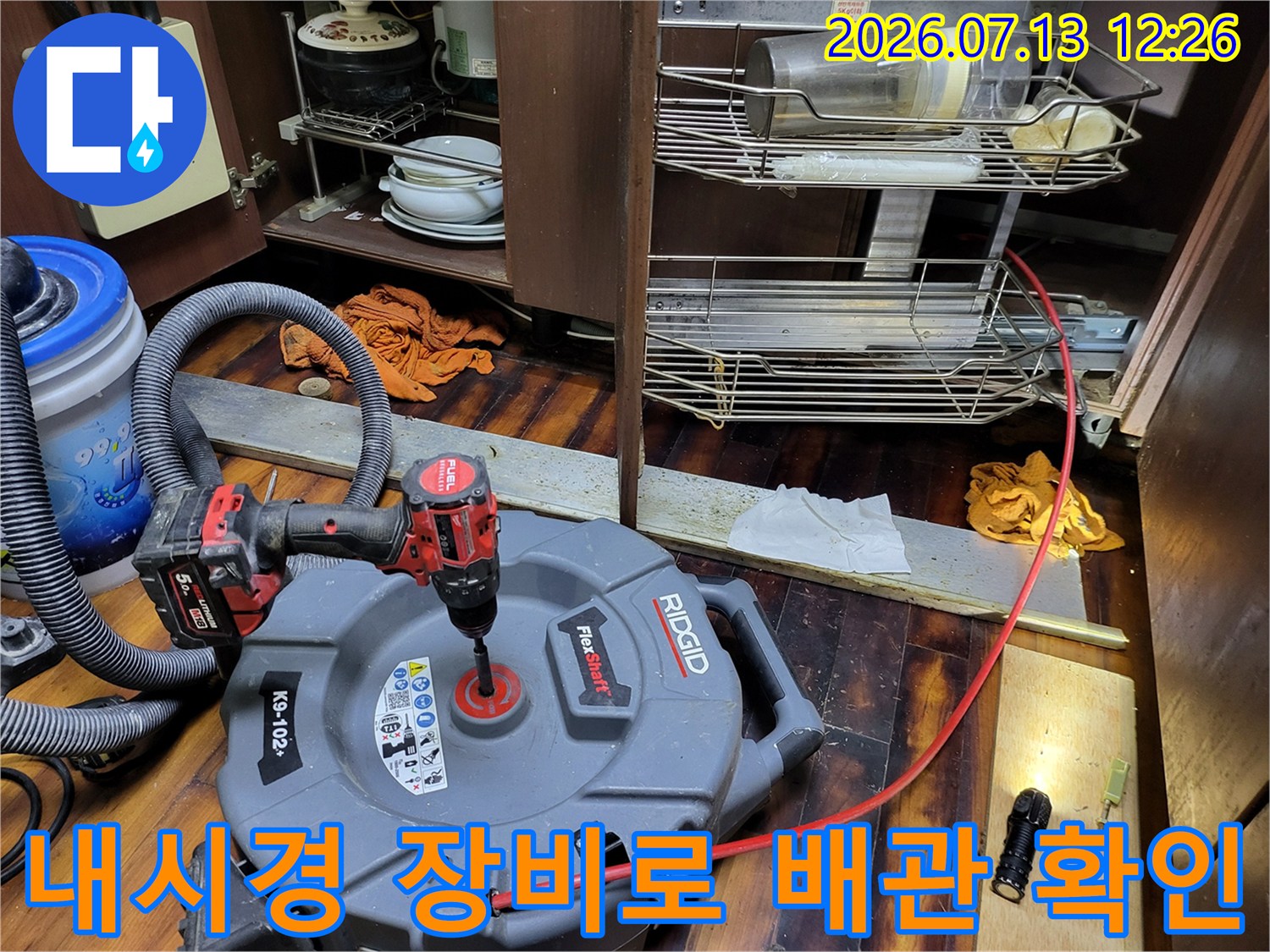 싱크대 하부 공간에서 내시경을 통해 배수관 내부를 점검하는 모습