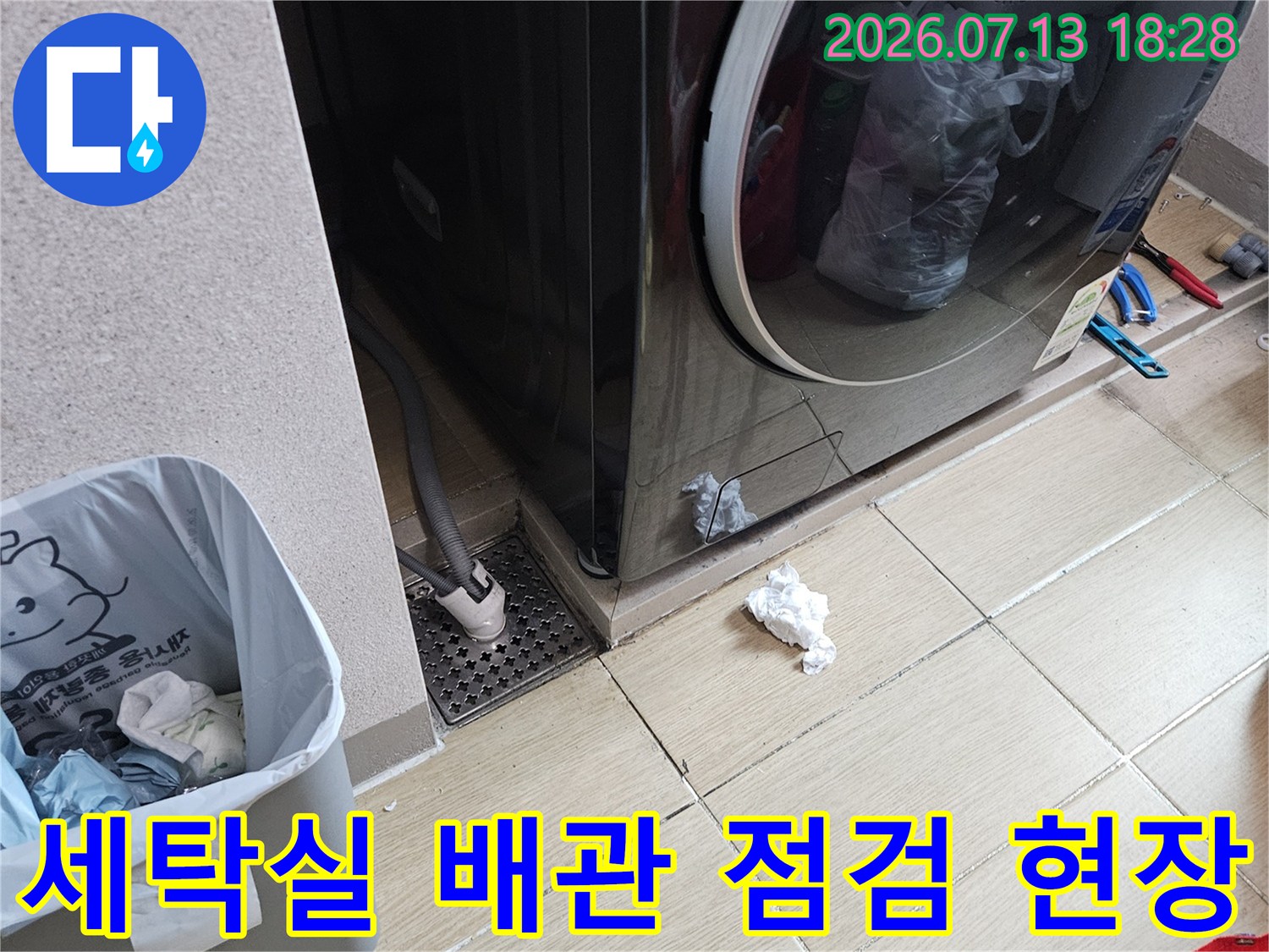 세탁기 옆에 위치한 배관과 주변 바닥을 점검하는 누수 탐지 현장
