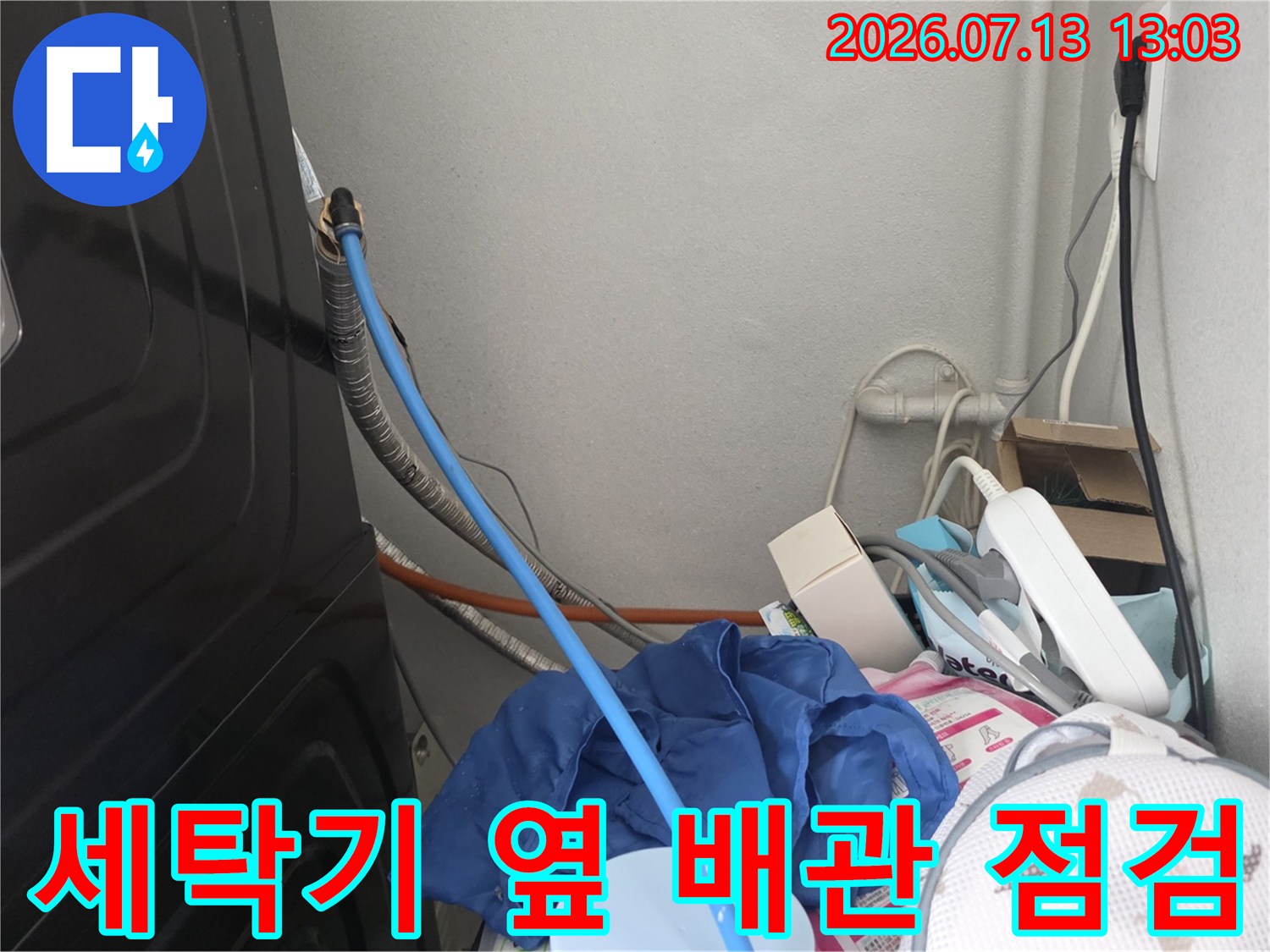 세탁기 옆 공간에서 파란색 호스로 압력을 체크하는 누수 진단 장면