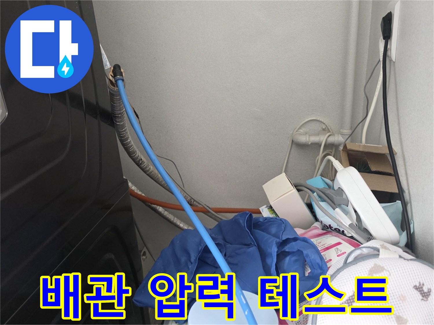 세탁실 배관에 연결된 파란색 호스와 주변 배관 구조물