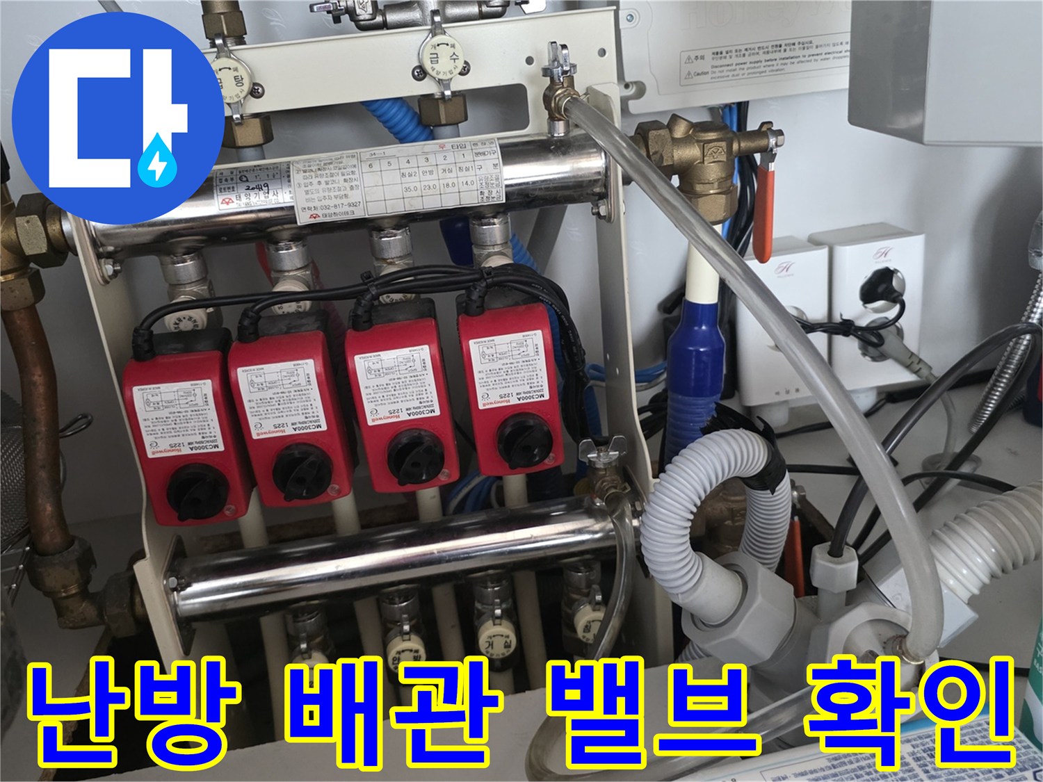 분배기에 설치된 붉은색 유량 조절 장치와 하단부 배관 연결 부위의 누수 여부를 관찰하고 있습니다.