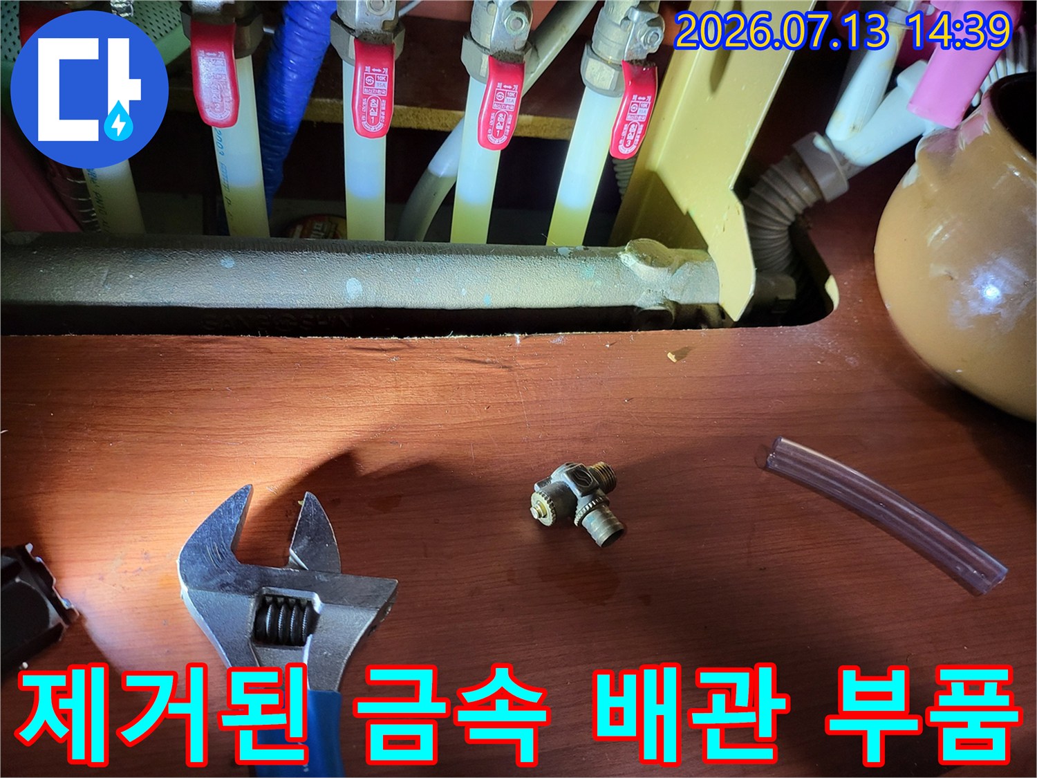 분배기에서 분리해낸 황동색 티자 조인트와 몽키스패너가 나란히 놓인 모습