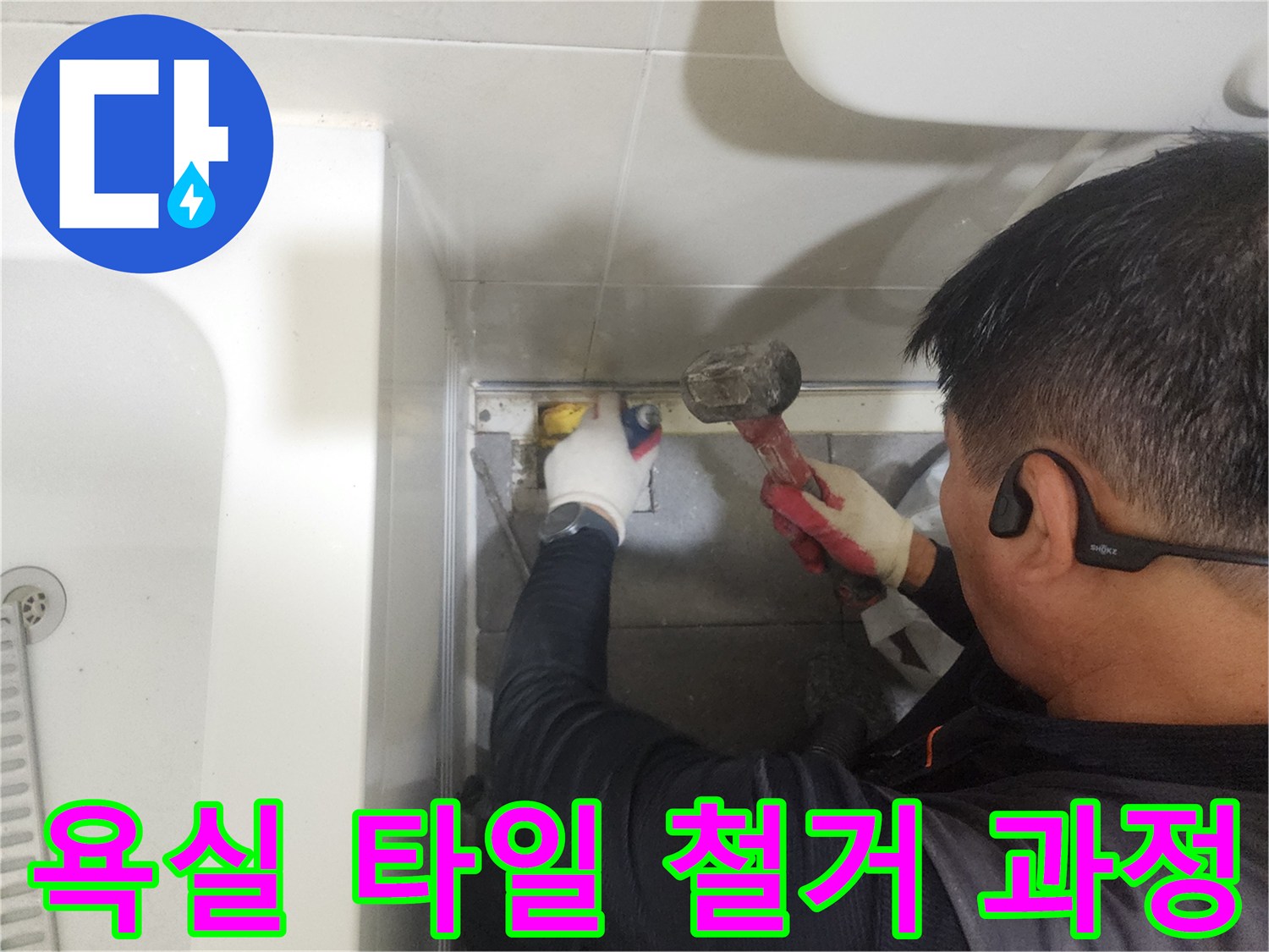 망치를 사용하여 욕실 배수구 주변의 낡은 마감재를 제거하는 모습