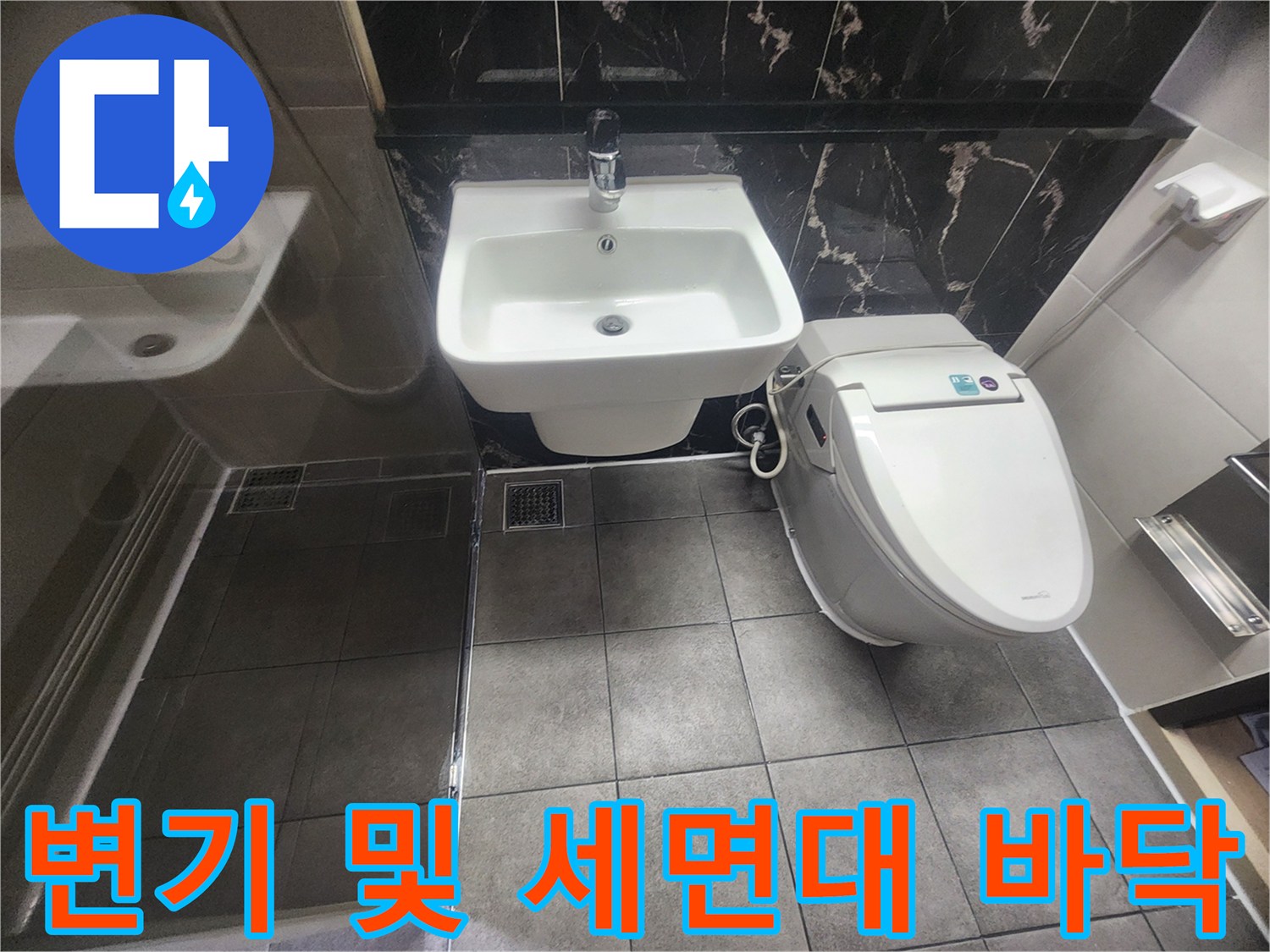 변기와 세면대가 설치된 욕실 바닥의 타일 마감 상태 - 누수 방지 작업 완료