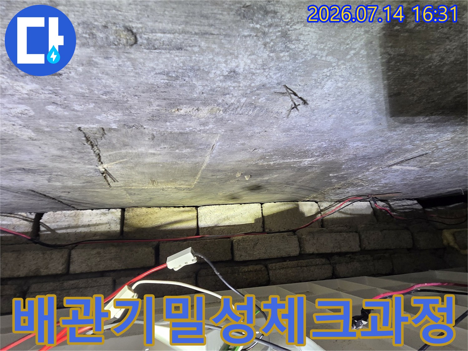 노출된 배관에 측정 장치를 연결하여 누수 여부를 정밀하게 점검하는 장면