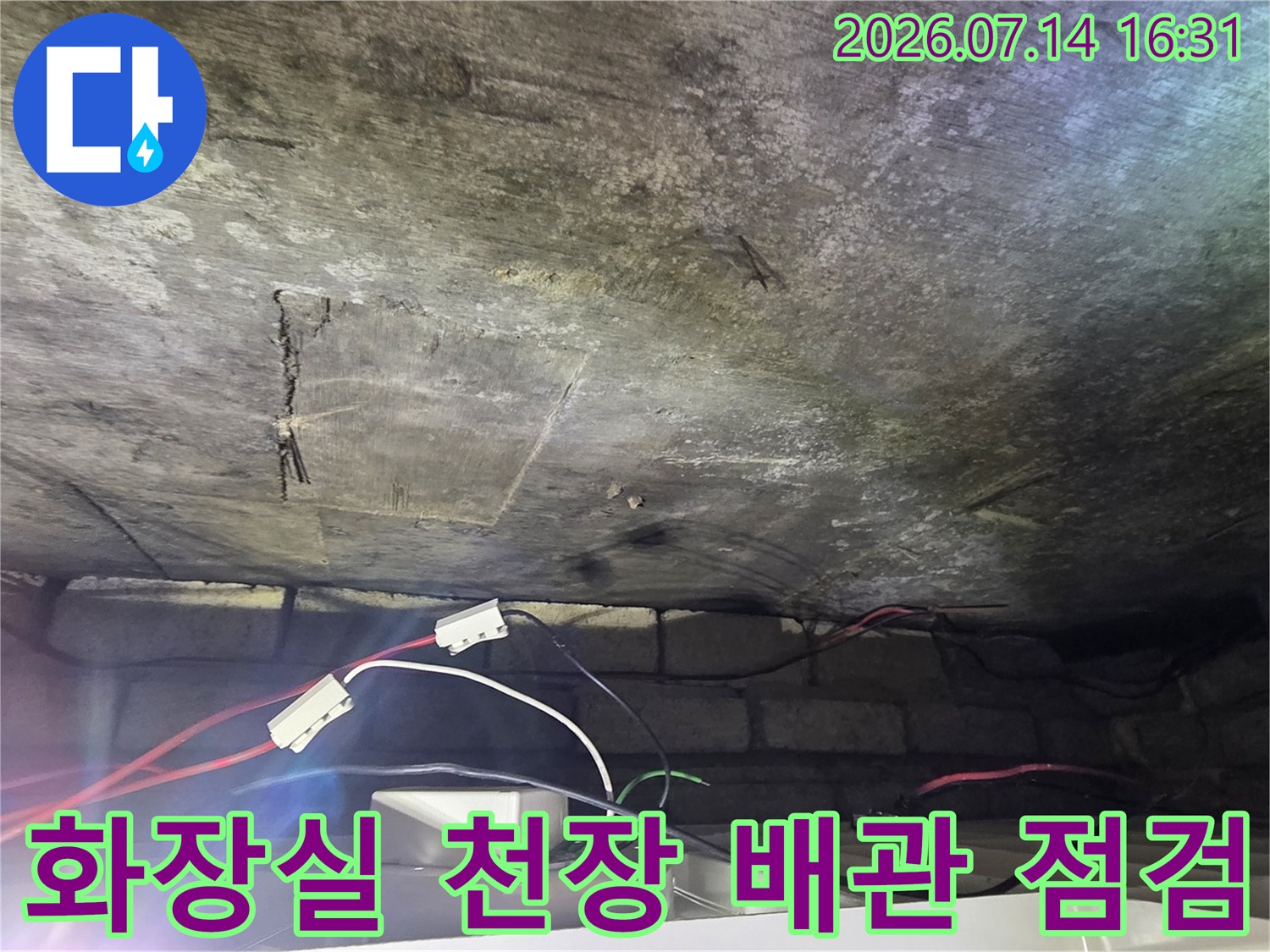 아랫집 화장실 천장 내부의 배관과 노출된 전선 및 공압 테스트 장비 모습
