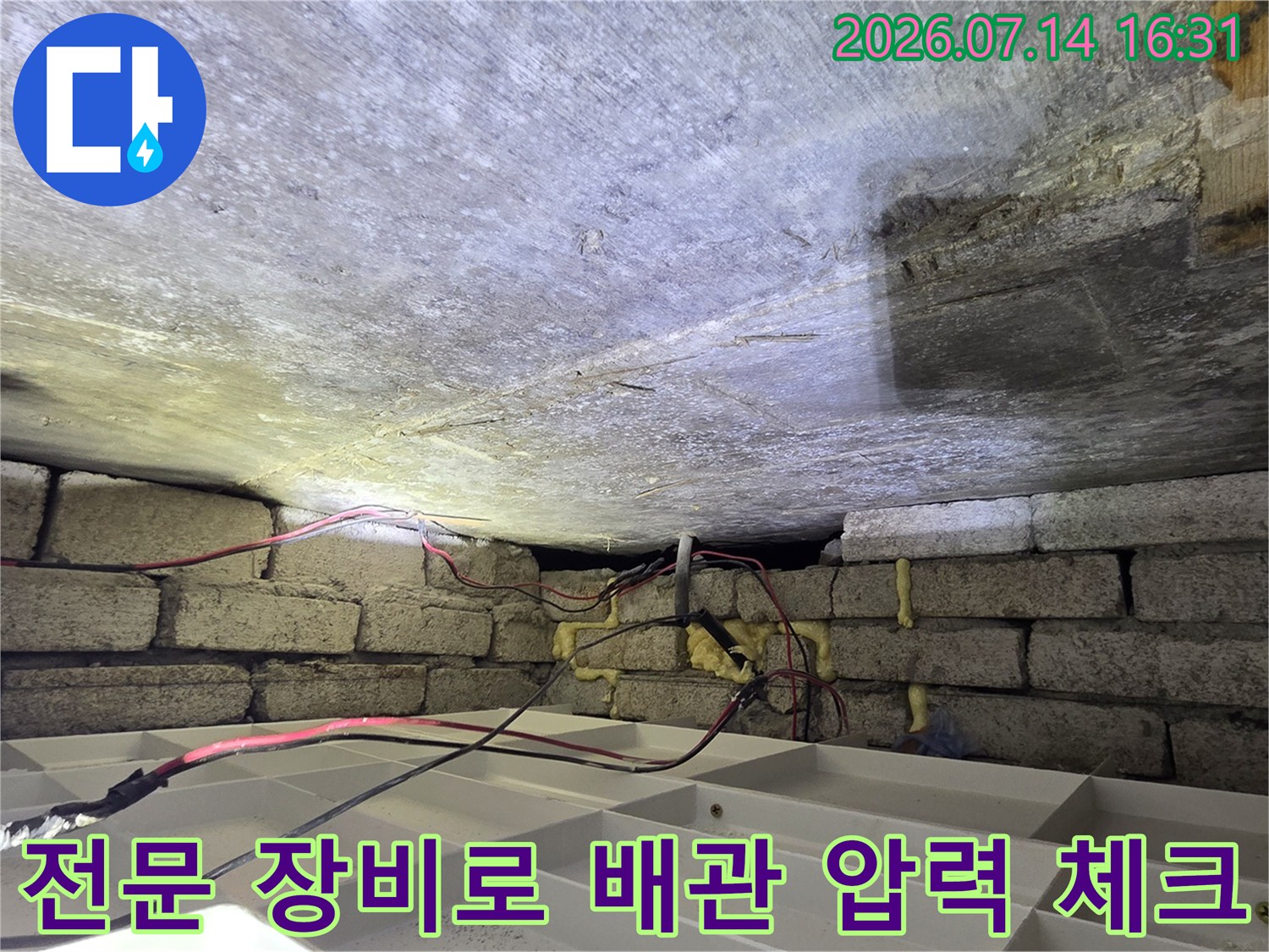 화장실 천장 내부에 노출된 배관에 호스를 연결하여 공압 시험을 진행하는 모습