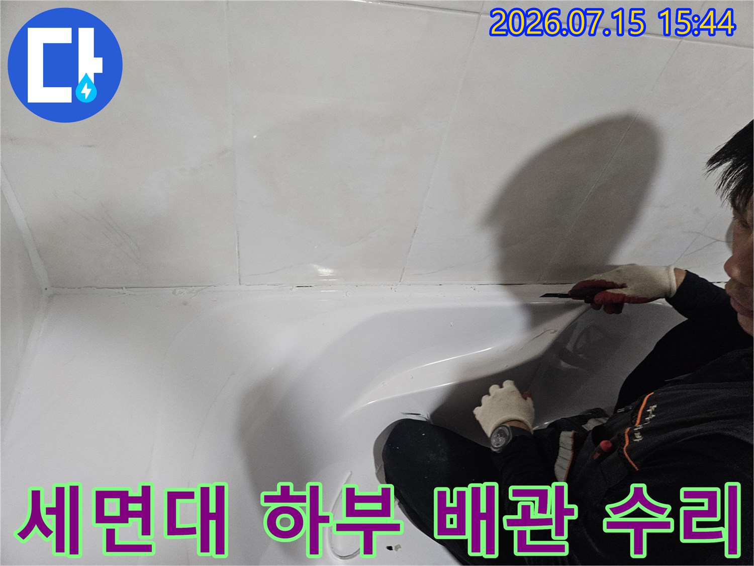 기술자가 세면대 아래 공간에서 누수가 발생한 배관 연결 부위를 정밀하게 점검하는 모습