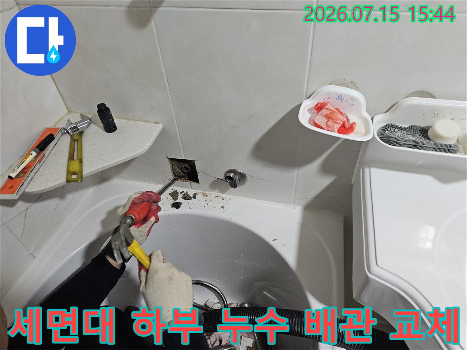 세면대 아래 노출된 배관의 파손 부위를 절단하고 새 부품으로 수리하는 모습