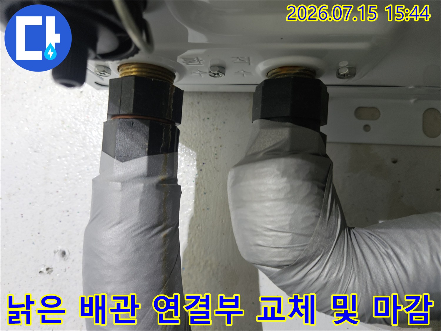 세면대 아래 위치한 노출된 수도 배관을 새 부속으로 갈아 끼우고 보호 테이프를 감은 모습