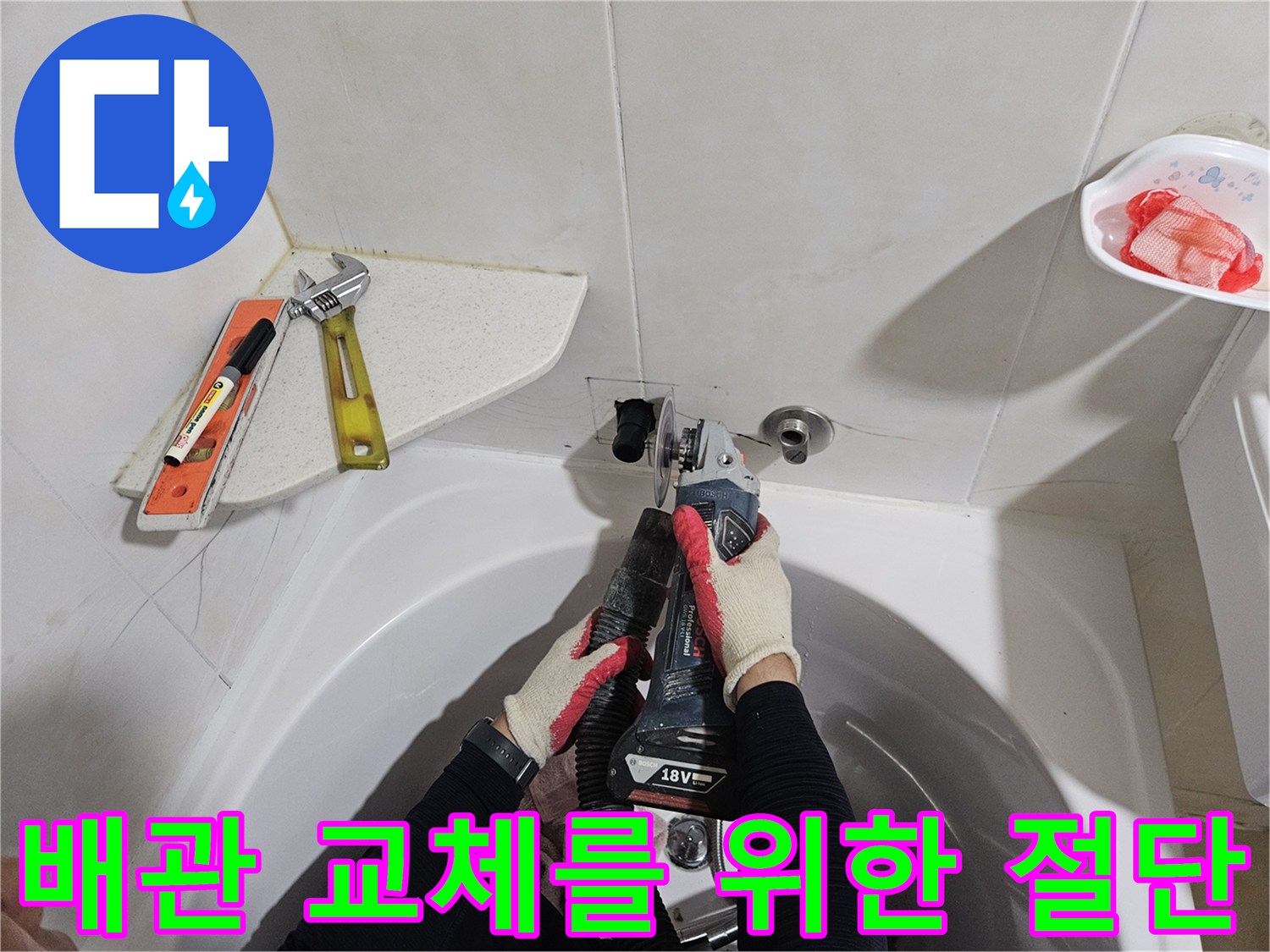 욕실 벽면의 배관을 자르는 공구와 작업자의 손