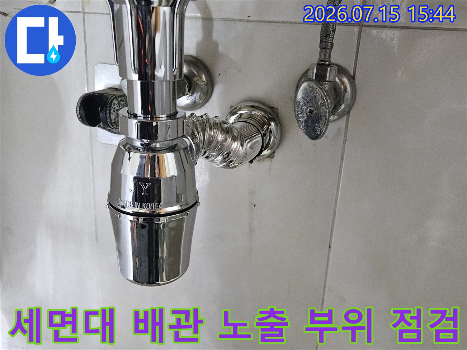 욕실 세면대 하부의 노출된 금속 배관과 연결 부위를 점검하는 모습