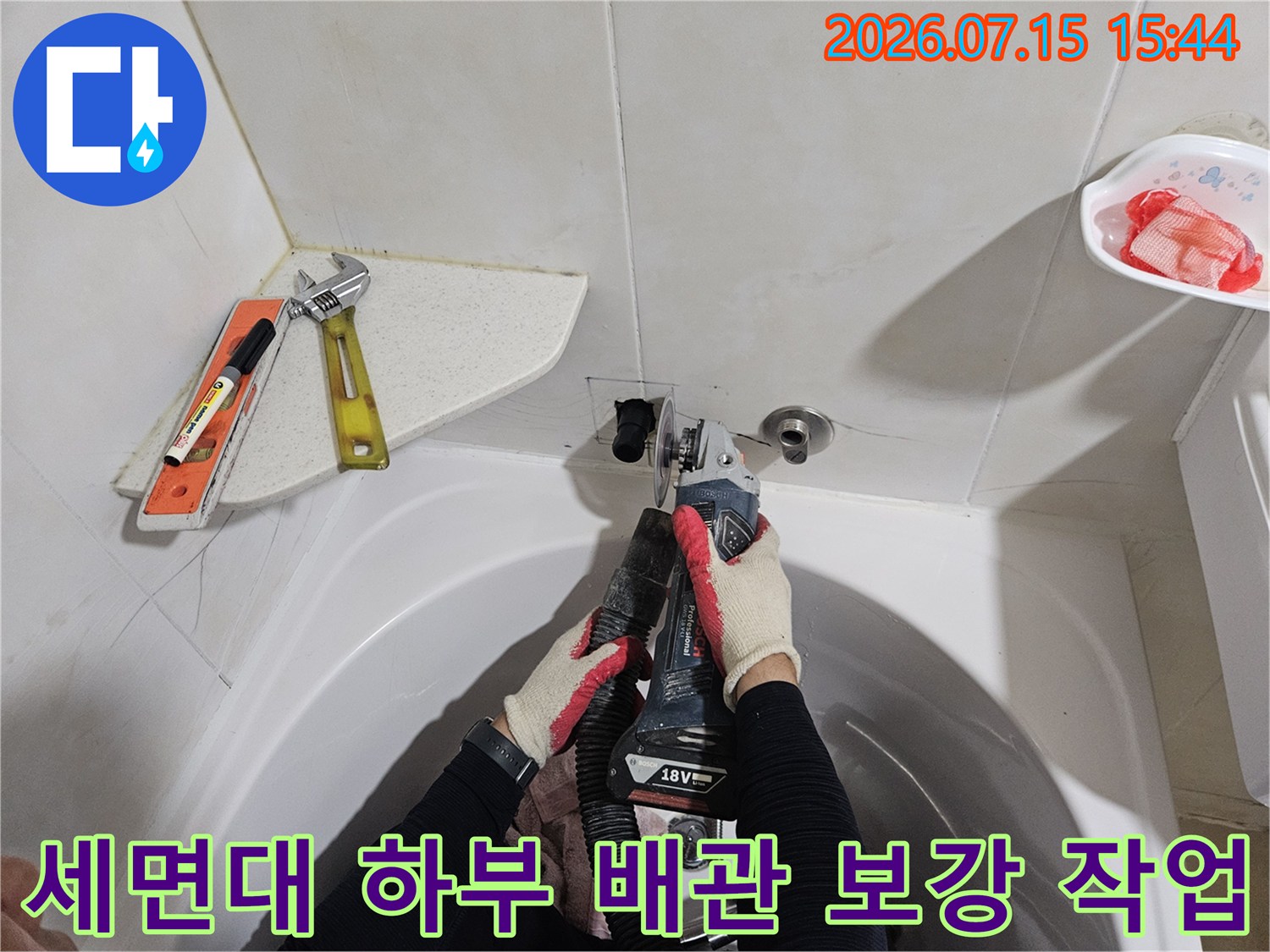 작업자가 세면대 밑으로 들어가 노후된 배관 연결 부위를 정밀하게 수리하는 장면