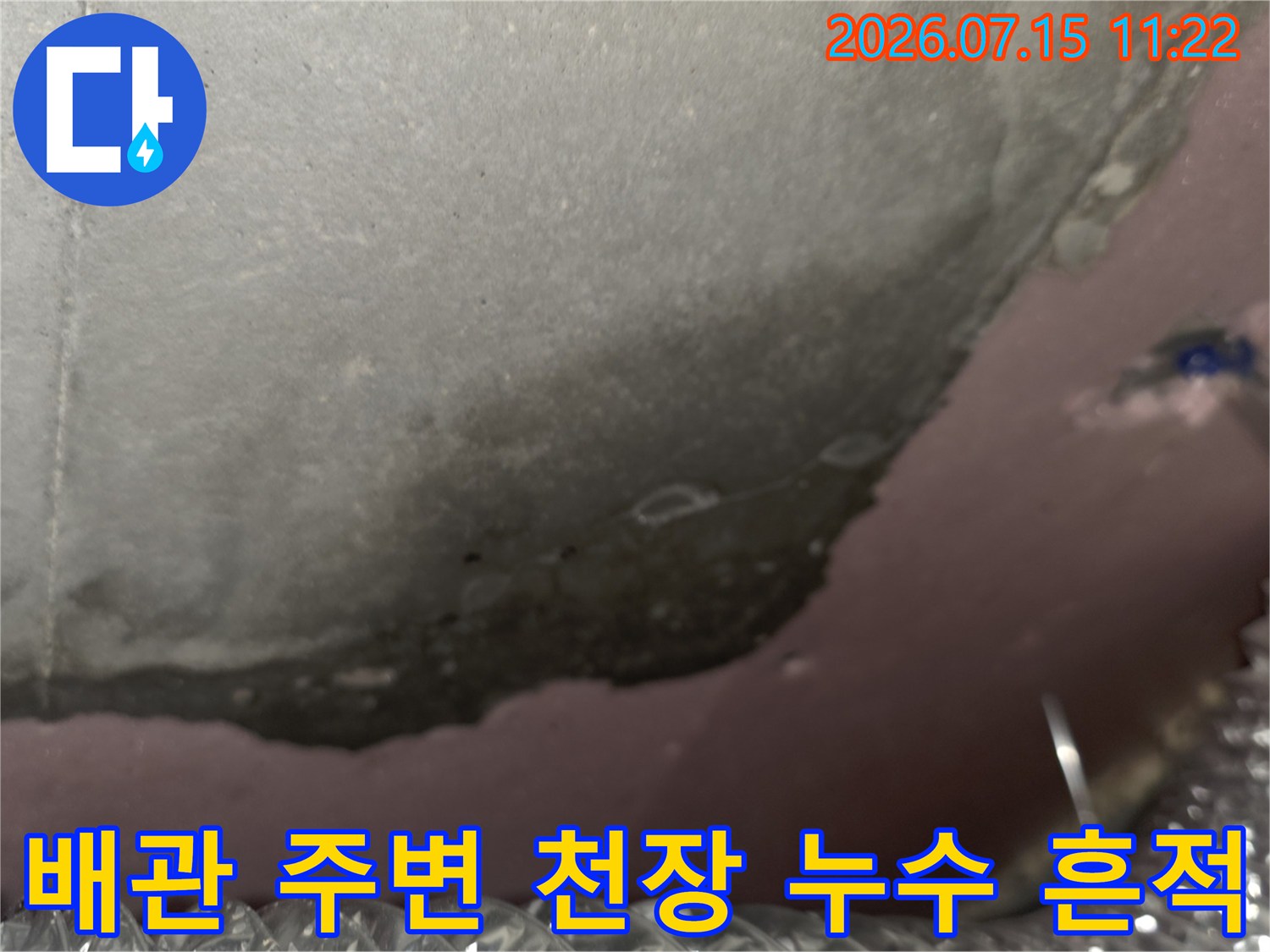 천장 속 좁은 공간의 배관과 그 주변에 생긴 어두운 습기 자국
