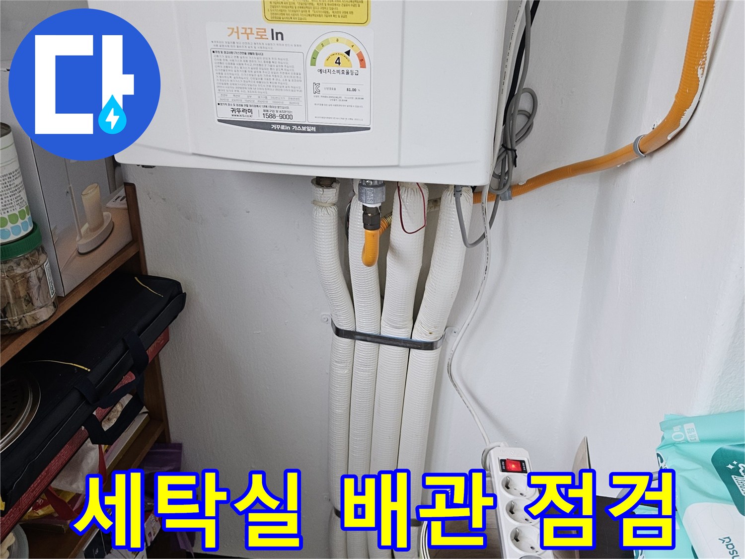 세탁기 주변의 하얀색 배관과 멀티탭이 놓여 있는 모습입니다.