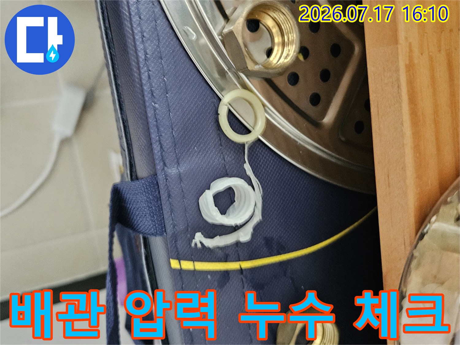 황동 소재의 배관 연결 부위에 공압 테스트용 장치를 부착하여 점검하는 현장 모습입니다.
