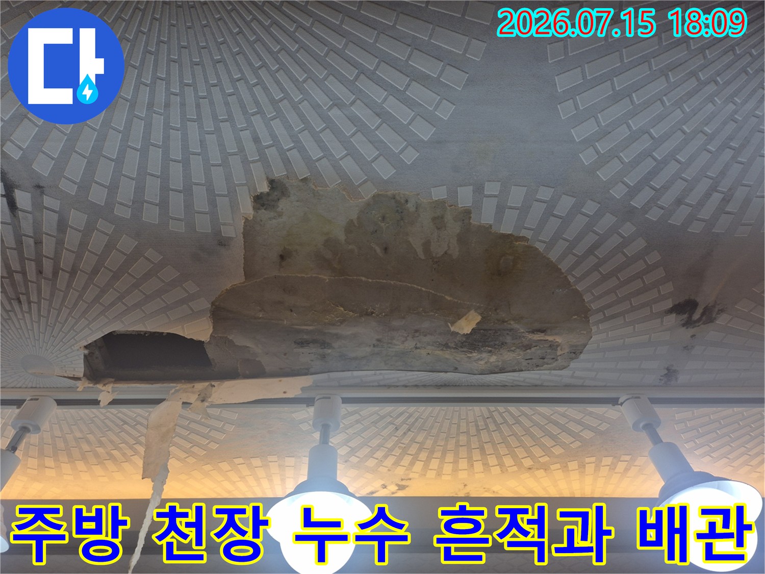 주방 천장 마감재가 훼손되고 물에 젖어 변색된 부위와 노출된 배관의 모습