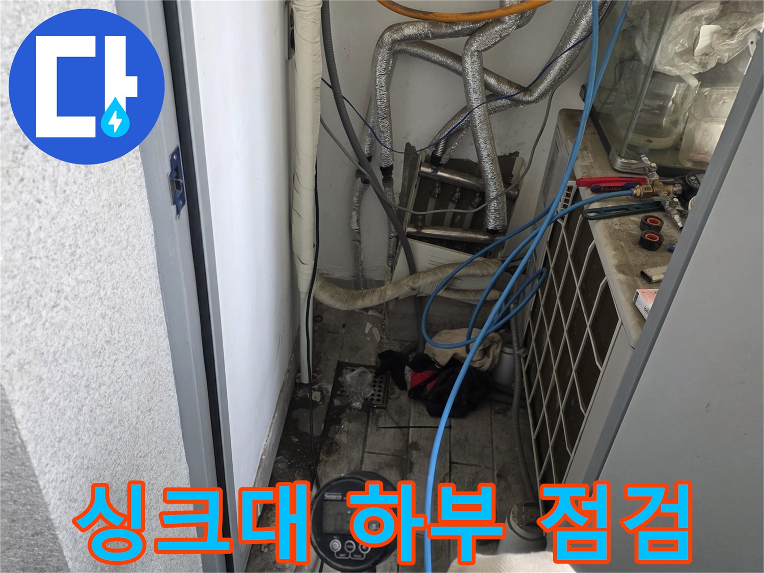 청색 호스와 게이지를 활용한 싱크대 하부 배관 검사 장면