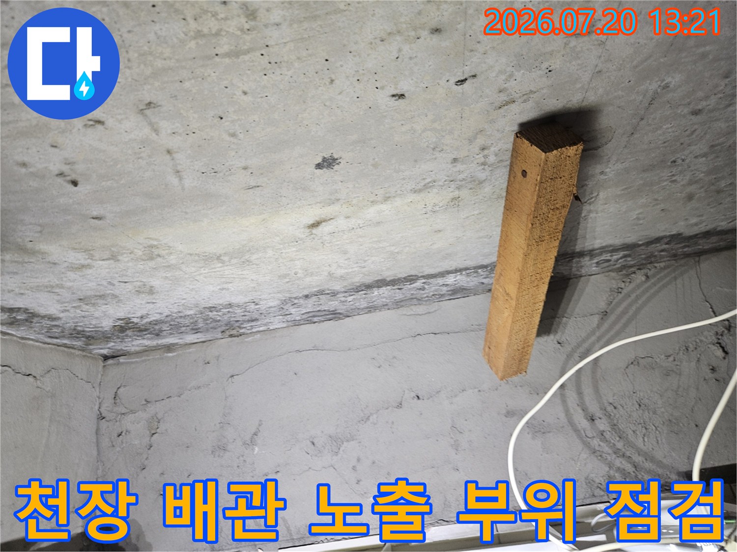 콘크리트 천장과 나무 지지대 그리고 배관이 지나가는 구간의 근접 촬영 사진