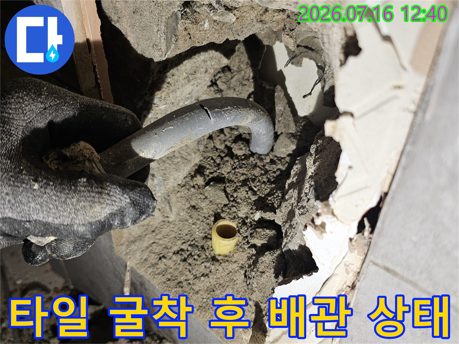 손상된 타일 벽면 내부에 노출된 파손 배관 구간