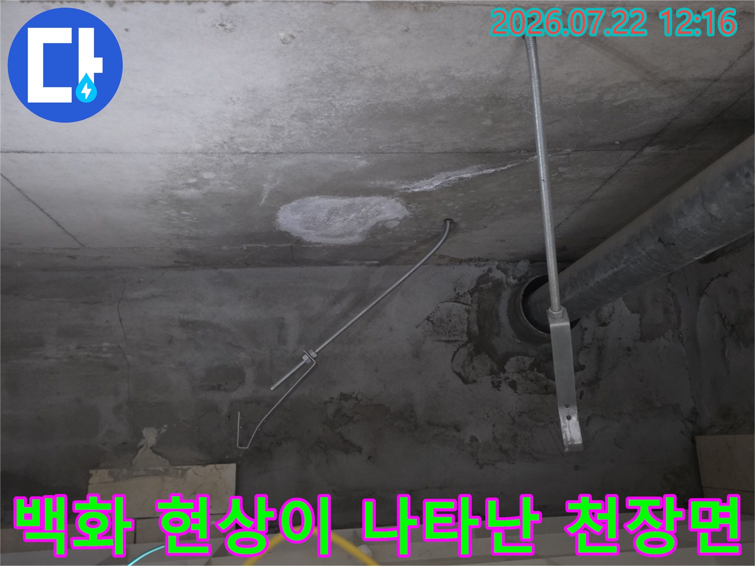천장 콘크리트 슬래브에 형성된 누수 얼룩과 수직 배관 라인