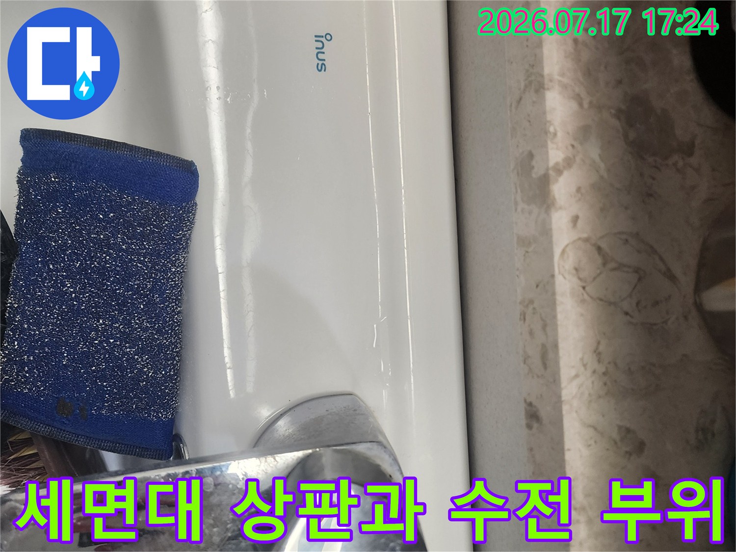 세면대 위에 놓인 파란색 스펀지와 은색 수도꼭지