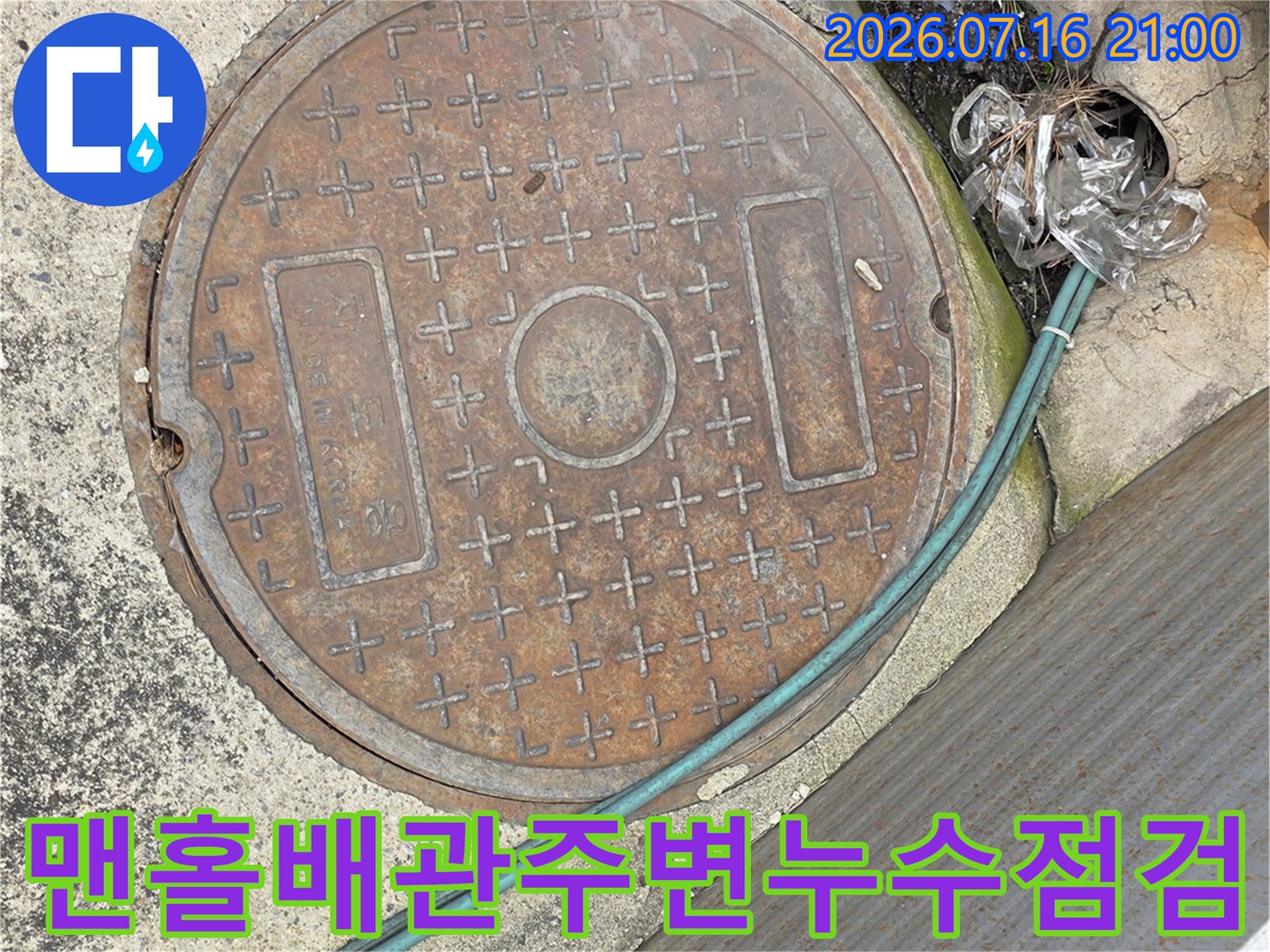 맨홀 뚜껑 주변으로 노출된 배관과 수분 흔적을 점검하는 모습