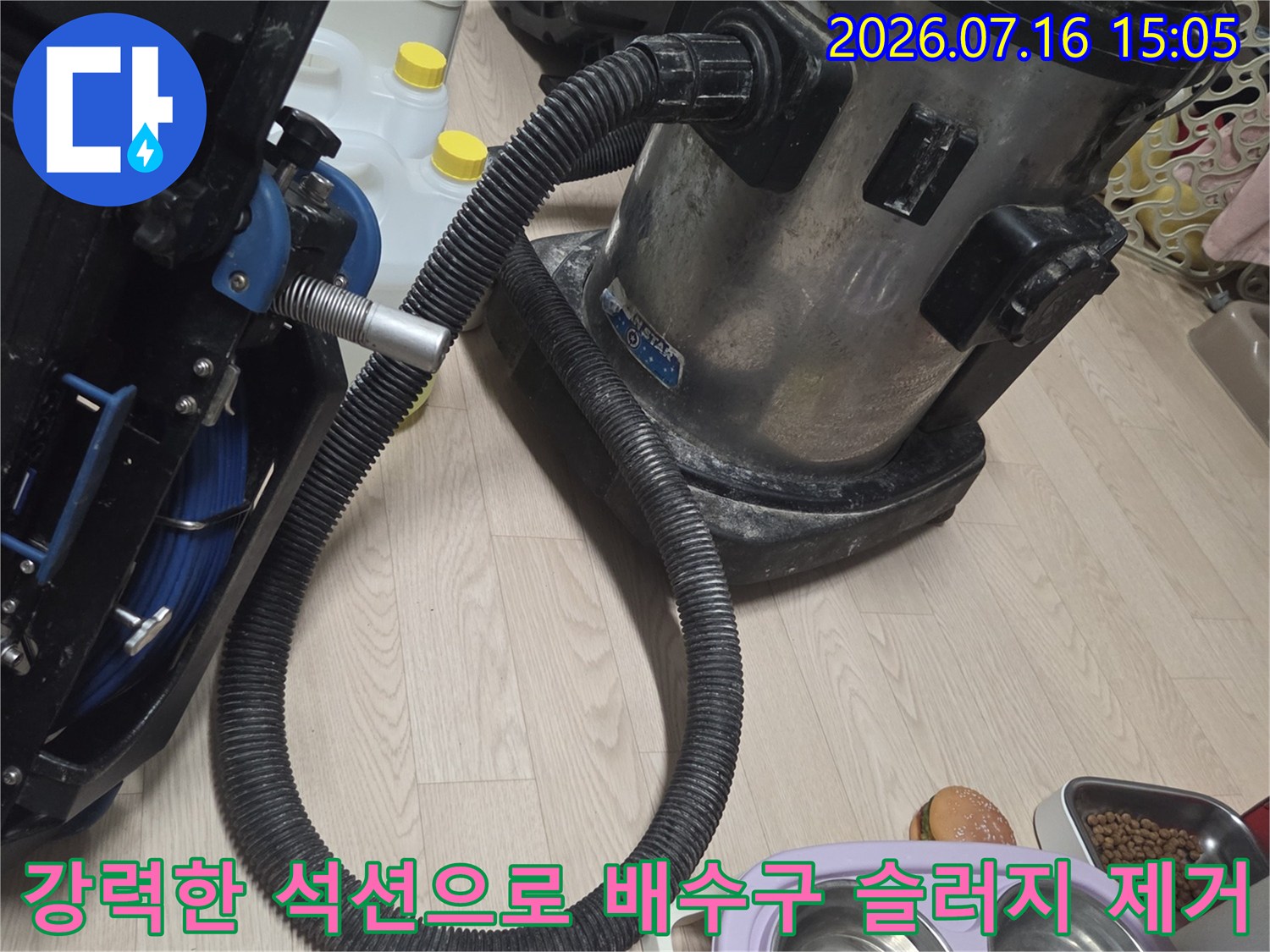 전문가 장비를 사용하여 싱크대 하단 배관의 오염물을 강력하게 흡입하는 장면