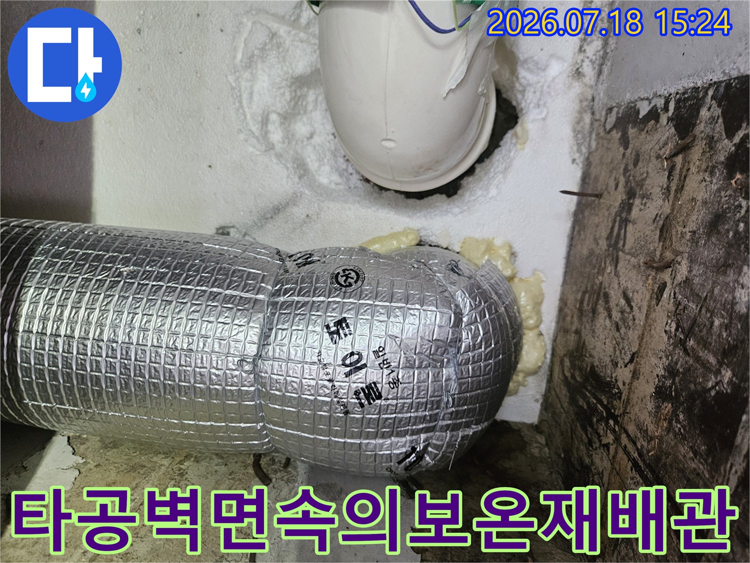 은색 보온 재료로 감싸진 배관과 벽면 타공 부위의 모습