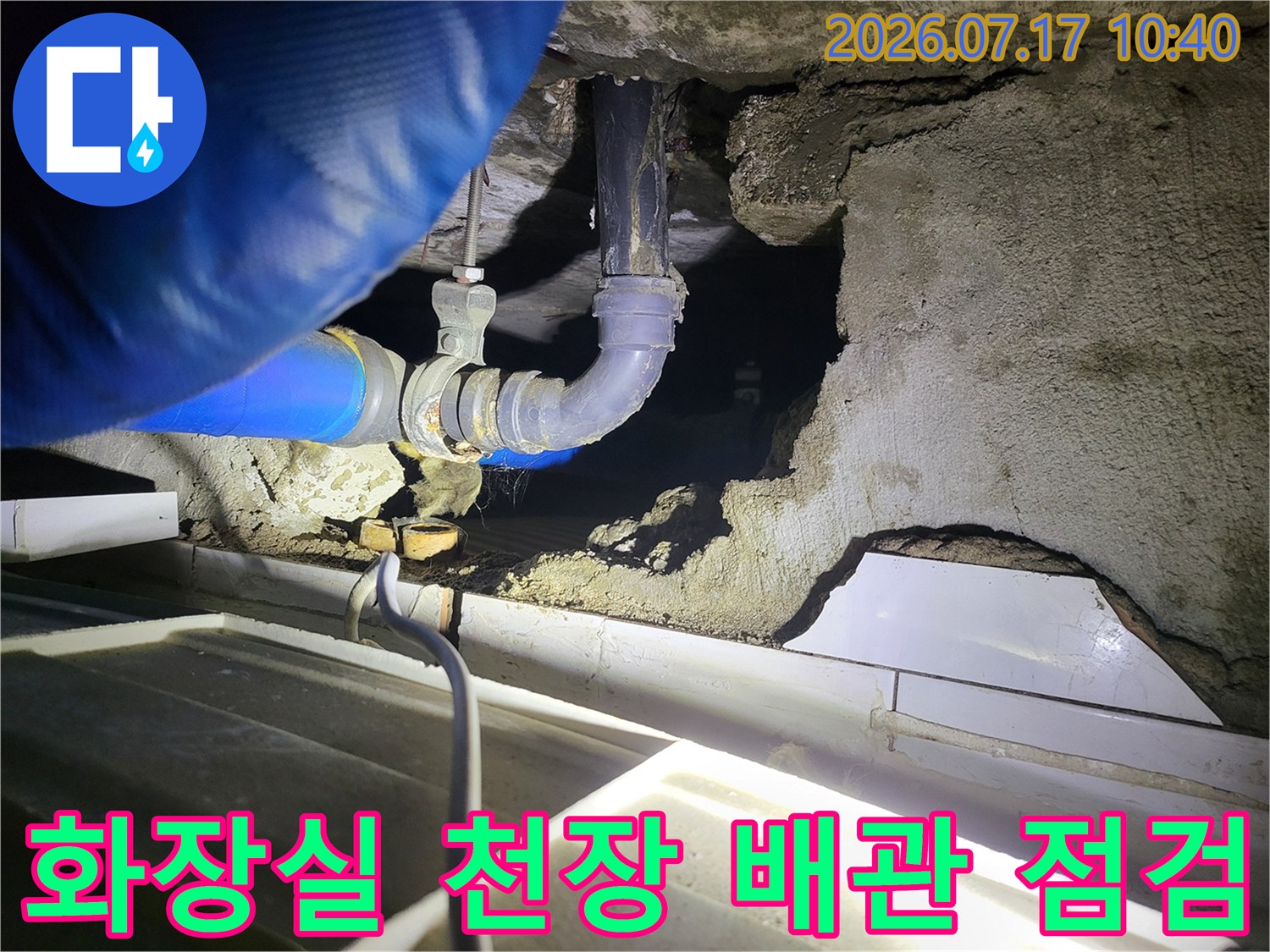 화장실 천장 내부의 파이프 연결 부위와 압력 테스트를 위한 장비가 배치된 모습