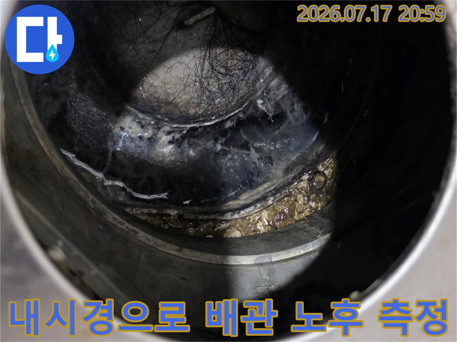 싱크대 아래 어두운 공간에서 내시경을 통해 배출 배관의 상태를 파악하는 장면