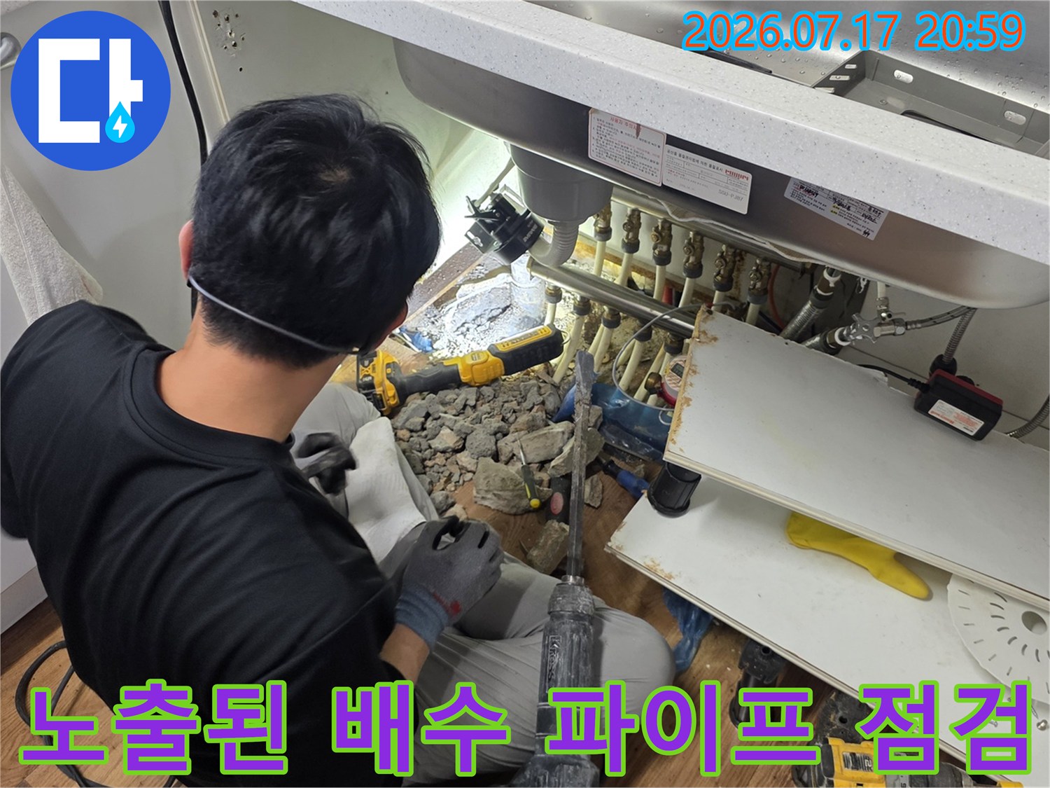 싱크대 하부 공간에서 엔지니어가 노출된 배수 시스템을 조사하는 모습