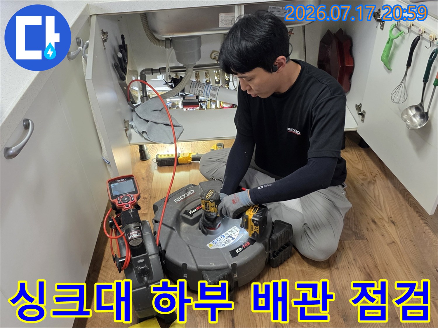 엔지니어가 싱크대 밑 공간에서 정밀 장비로 배수 시스템을 꼼꼼히 살피는 장면