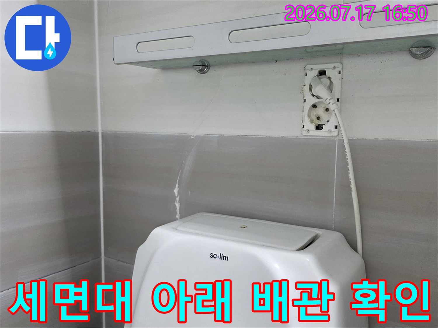 화장실 세면대 하부의 노출된 배관과 전선 구간을 정밀 점검하는 사진