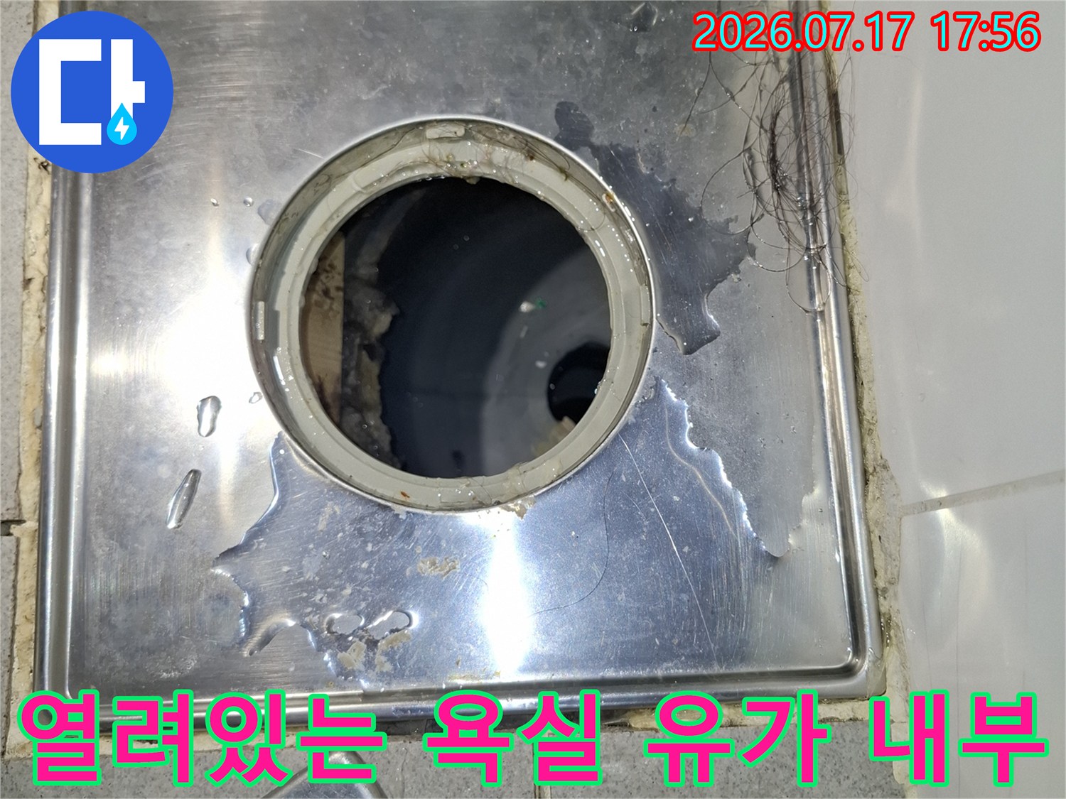 금속-배수구 덮개가 옆으로 치워져 있고 배관 입구가 노출된 사진