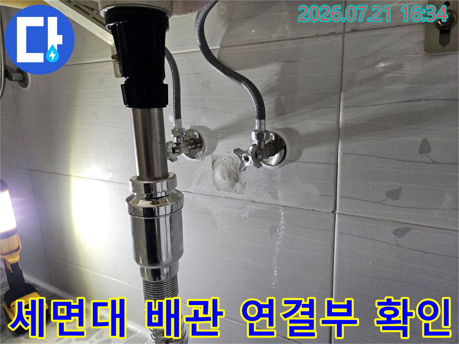 세면대 하단 배관과 벽면 밸브 연결 부위의 기밀 상태를 점검하는 모습