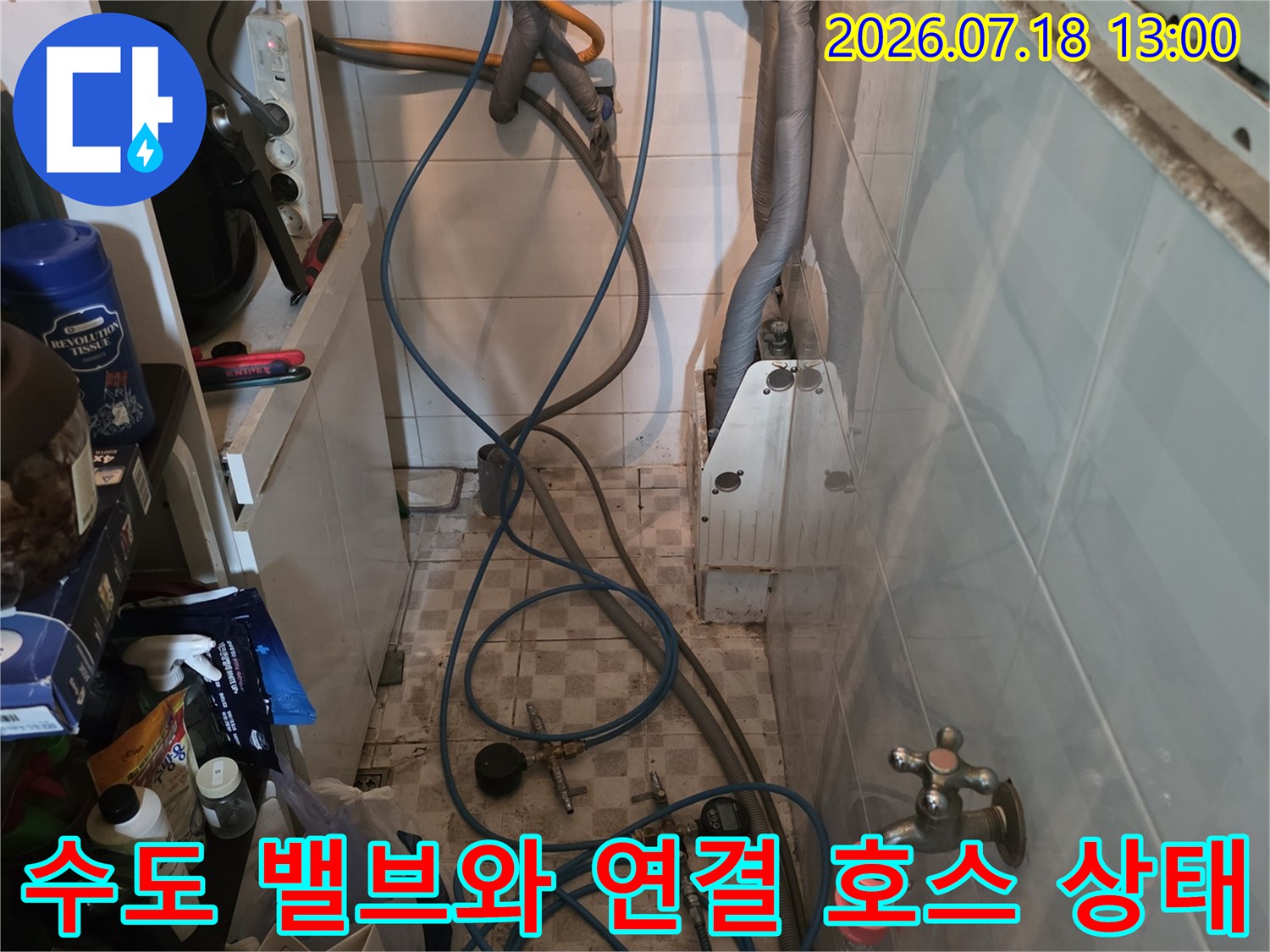벽면에 설치된 두 개의 수도 밸브와 아래로 늘어진 파란색 배관들