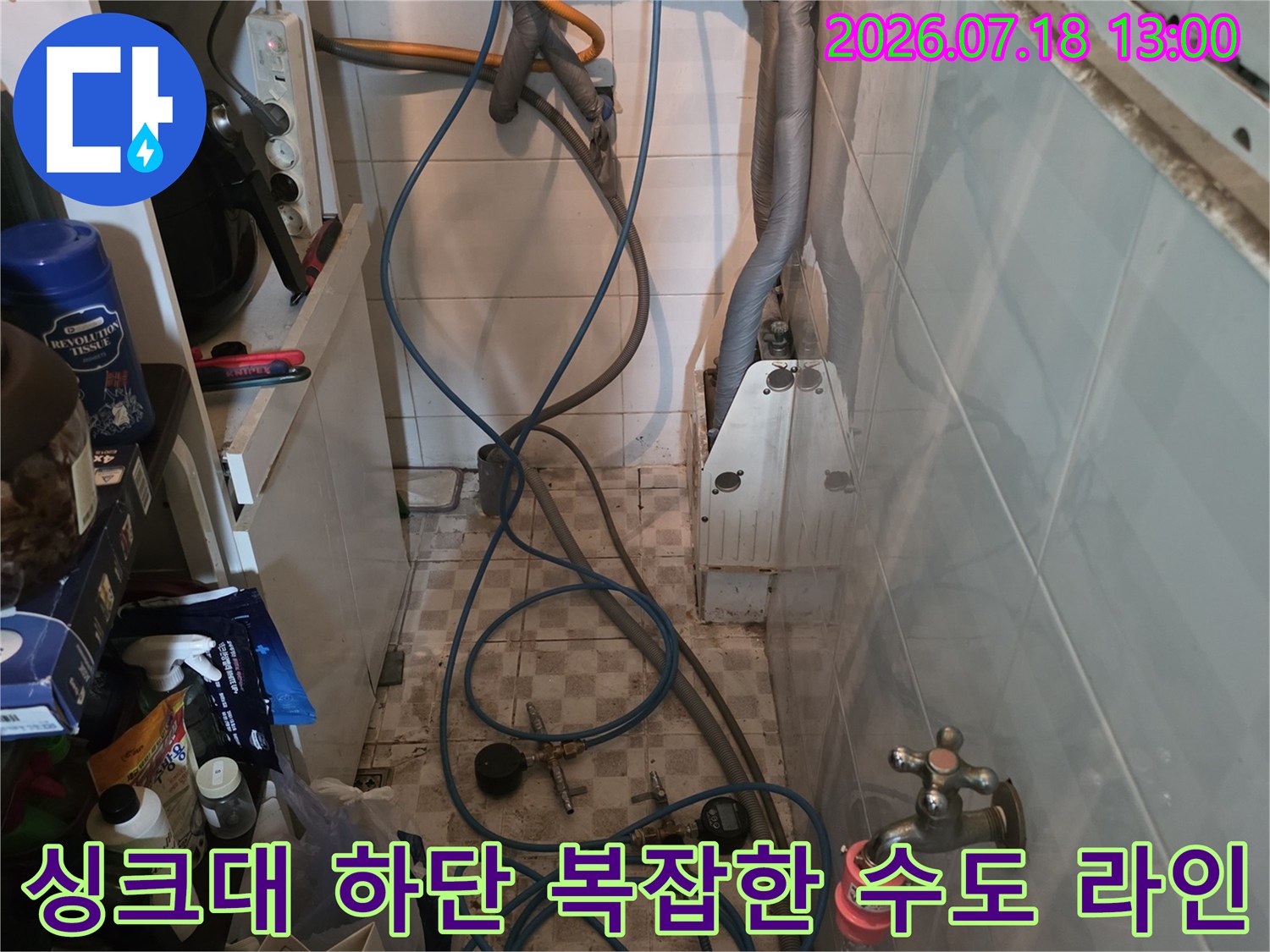 벽면의 금속 밸브와 여기서 시작되어 바닥으로 연결된 파란색 급수 호스들