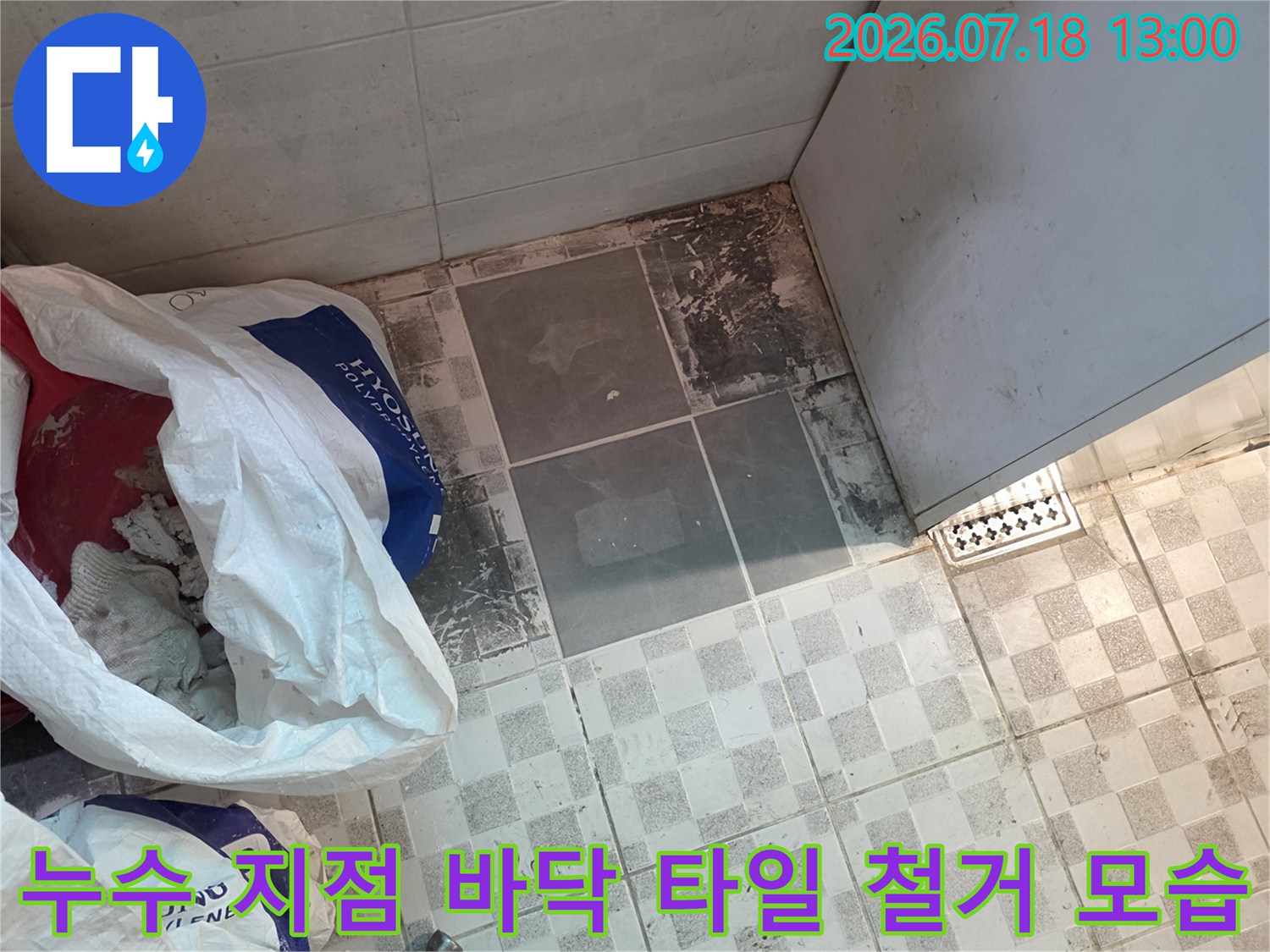 타일 바닥 일부가 제거되어 내부 슬래브가 드러난 누수 공사 현장 사진