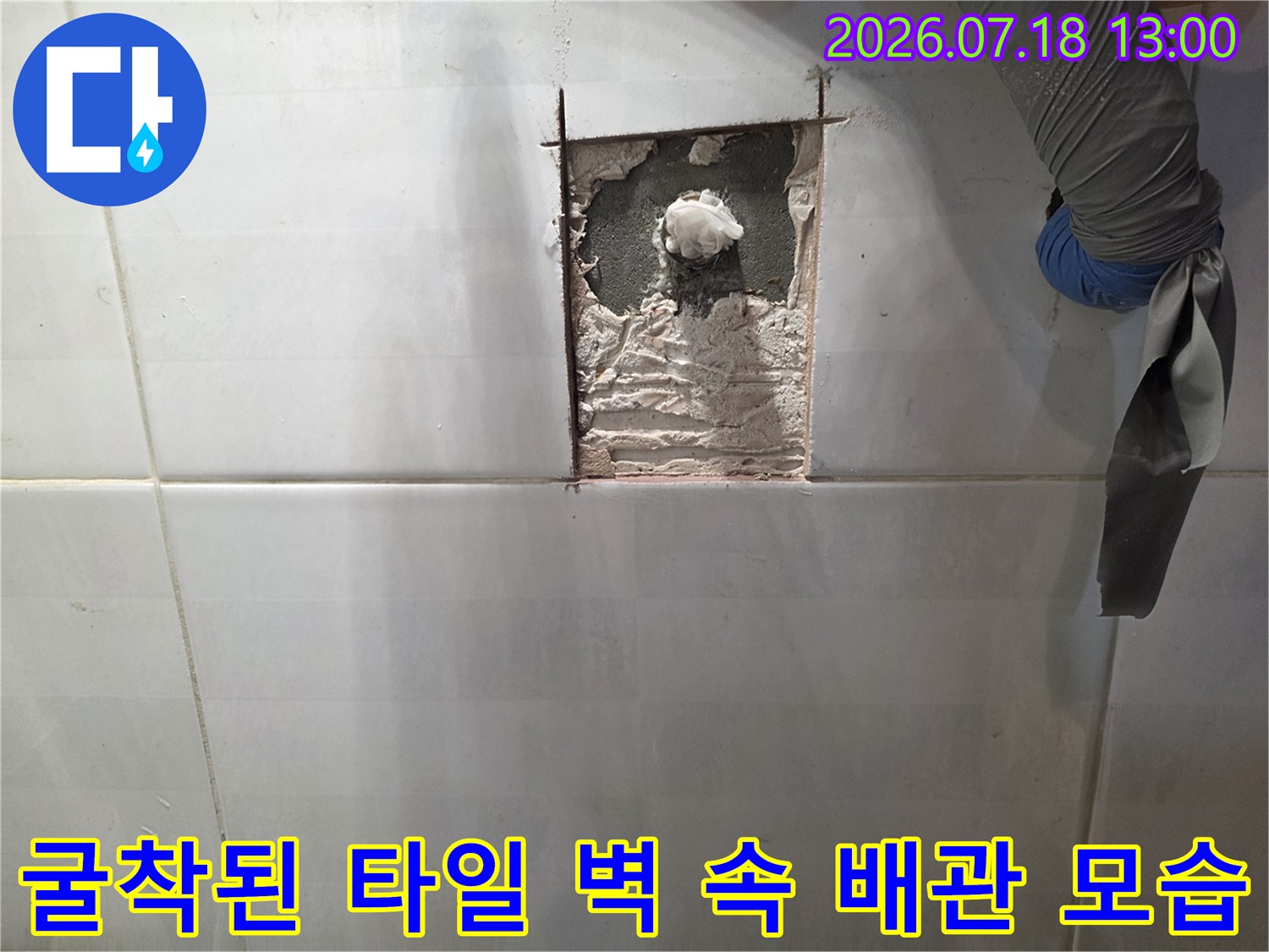 흰색 사각 타일 벽면에 직사각형 모양으로 구멍을 내어 내부의 흰색 배관이 노출된 사진