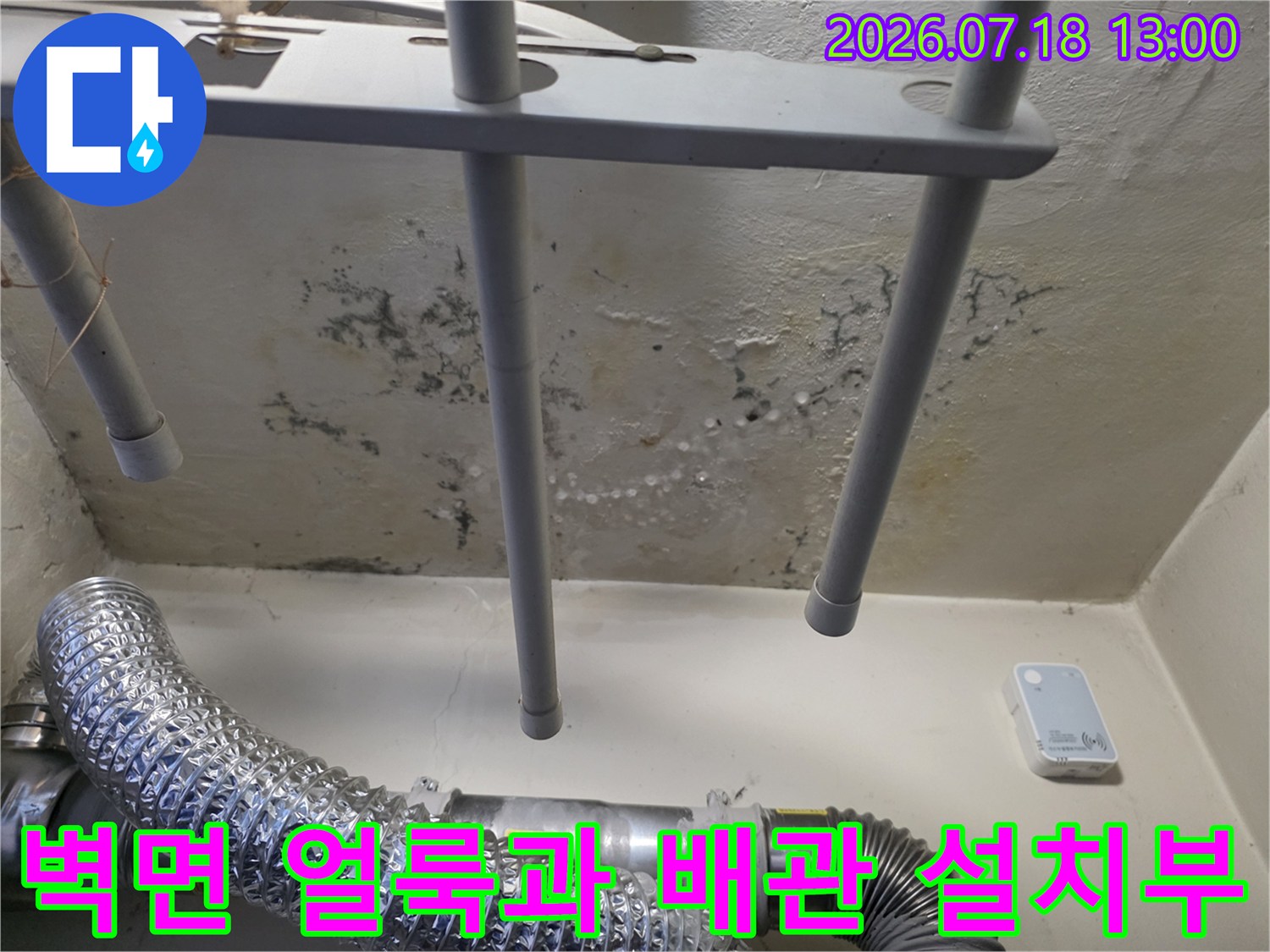 흰색 페인트 벽면에 물기가 스며들어 갈색 얼룩과 검은 곰팡이가 형성된 모습