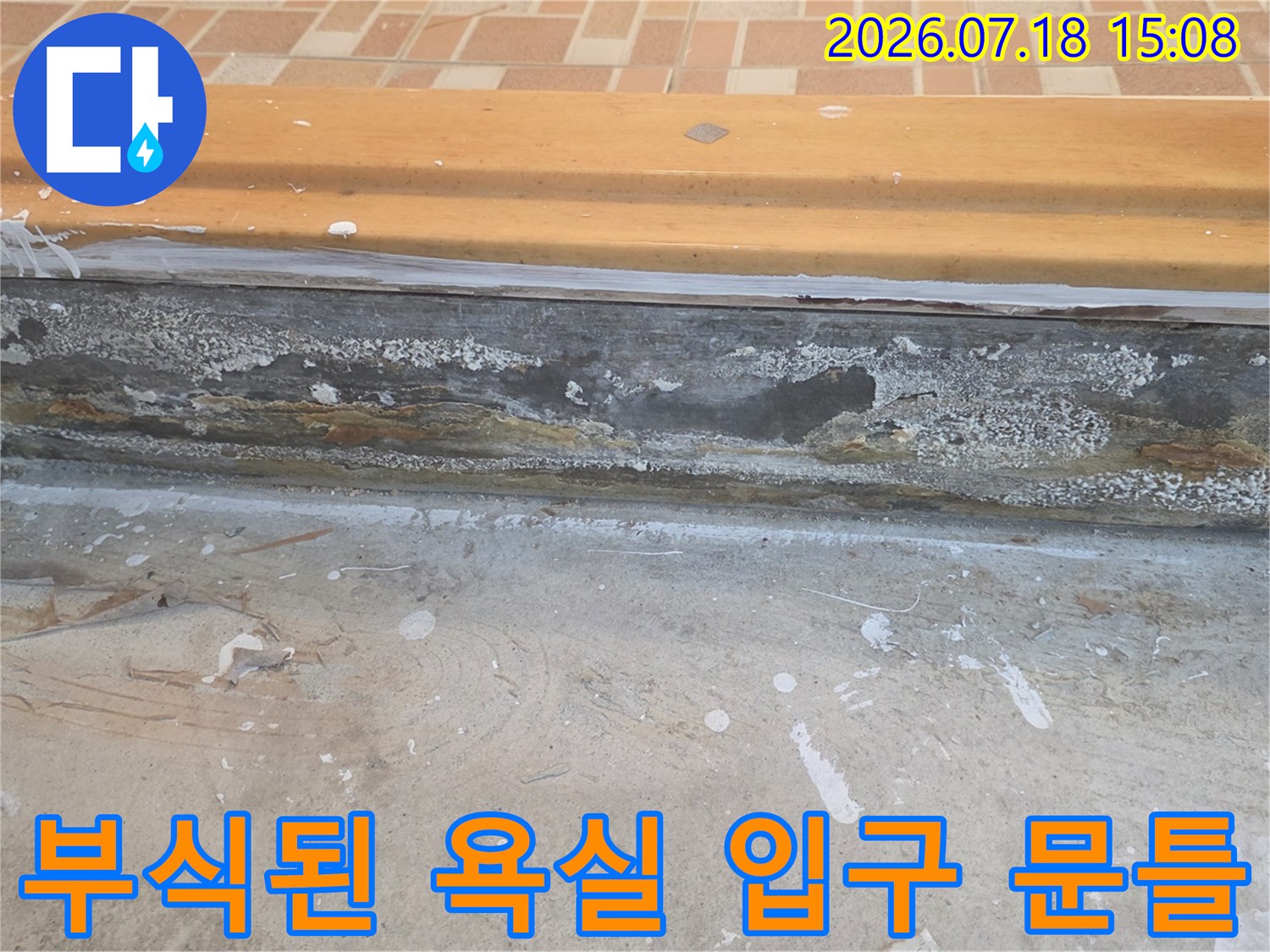 욕실 문턱의 하단부가 습기로 인해 껍질이 벗겨지듯 부식되고 변색된 모습