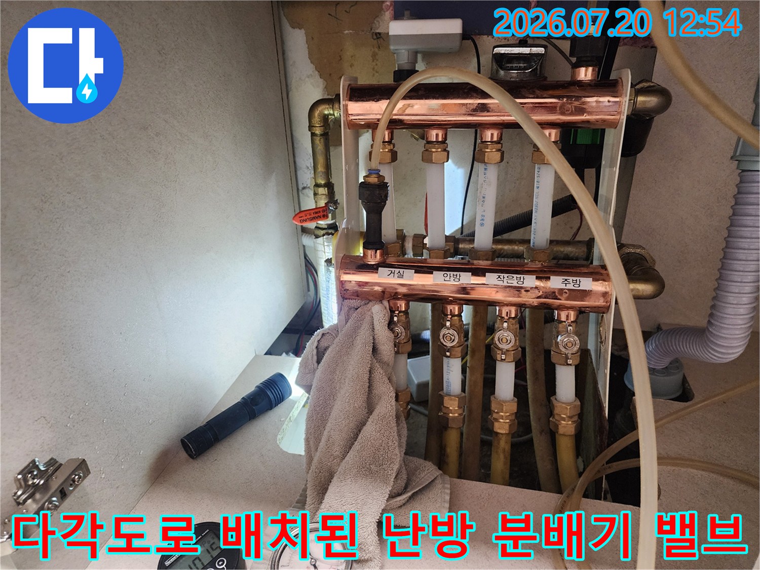 금속제 구리 파이프와 조절 밸브가 나란히 배열된 보일러 분배기의 정면 모습