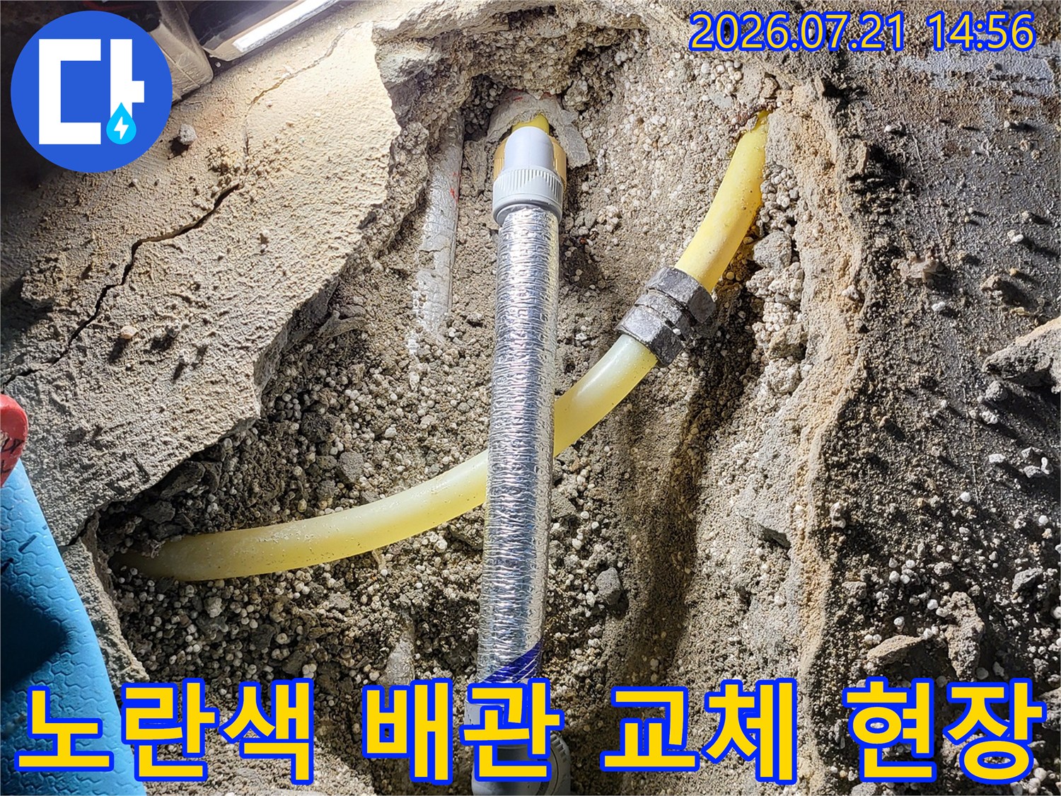 노란색 온수 배관과 은색 보온재가 덮인 배관 연결 부위를 수리하는 장면