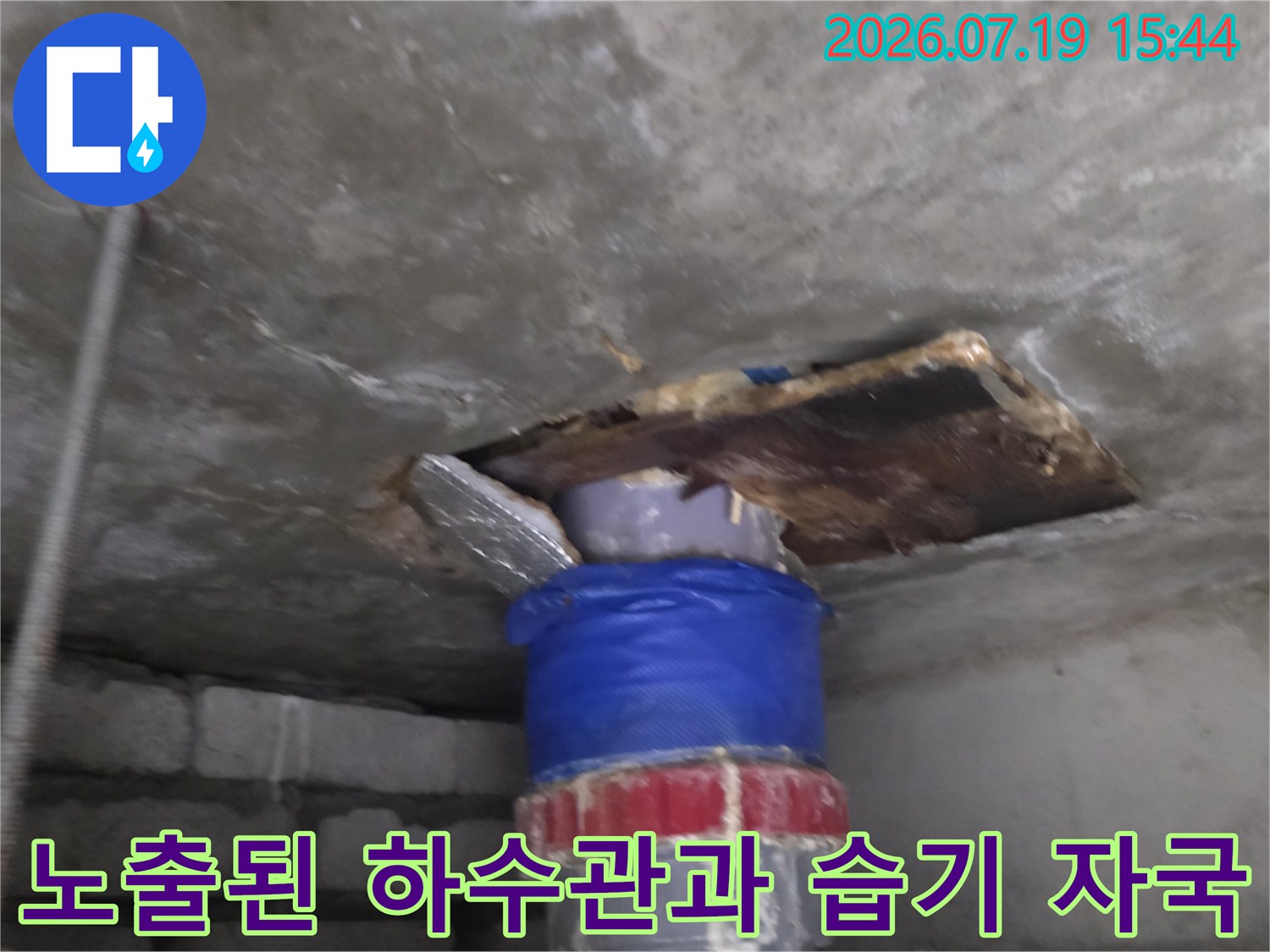 파란색 보온재로 감싸진 배관 주변으로 물기가 스며든 콘크리트 천장의 모습