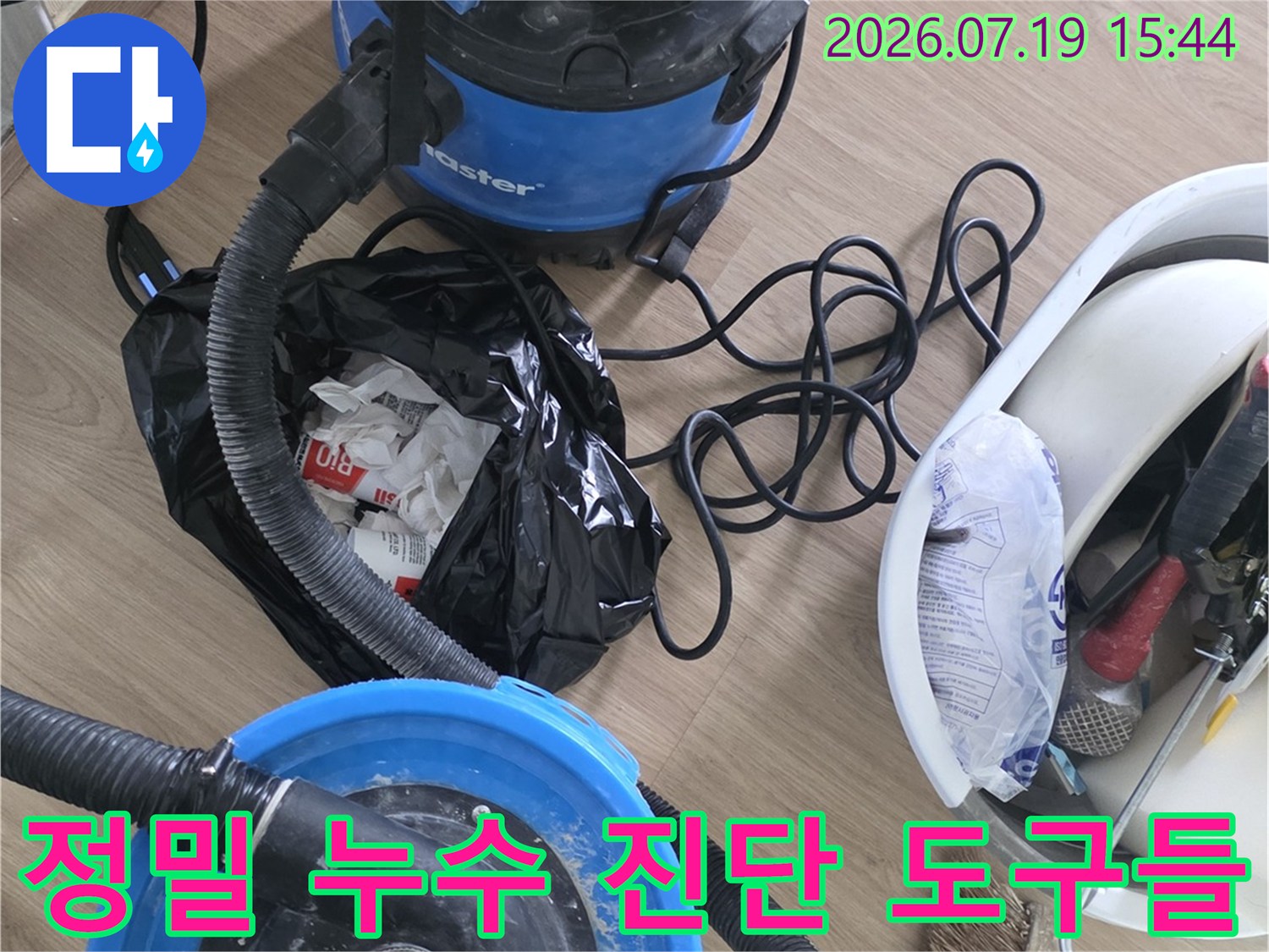파란색 산업용 청소기와 연결 호스-작업용 바구니가 놓인 현장 모습