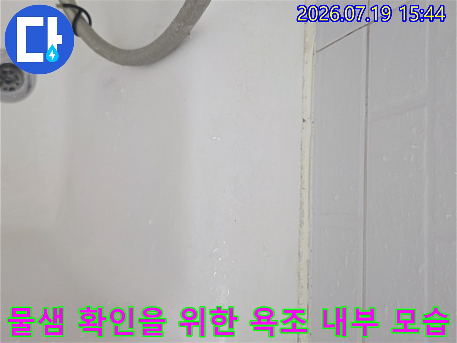 흰색으로 마감된 욕조와 배수구-회색 호스가 놓여 있는 상태