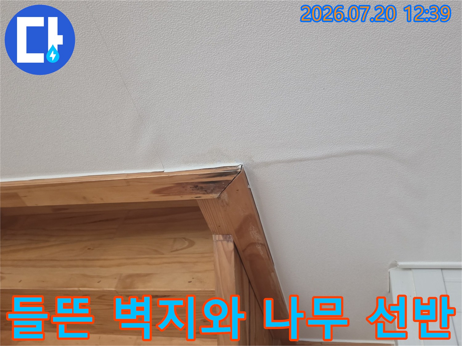 나무 소재의 가구 위쪽으로 벽지가 울퉁불퉁하게 들떠 있는 모습
