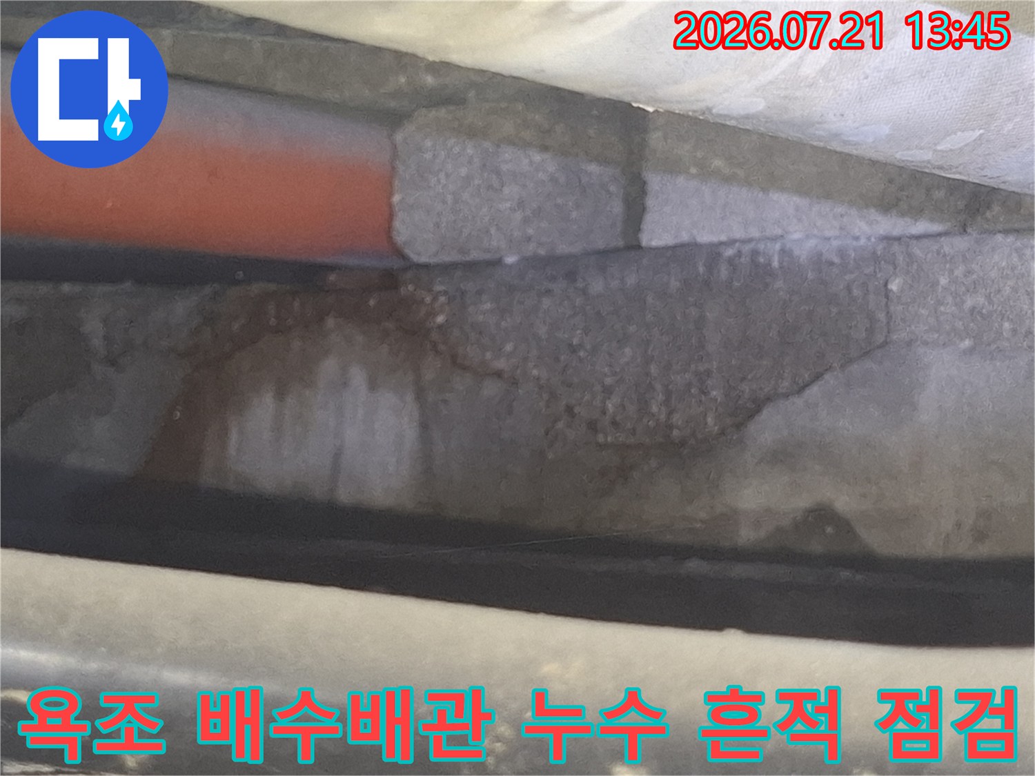 욕조 하부 배수배관 주변의 누수 흔적이 남은 콘크리트와 배관 구조물