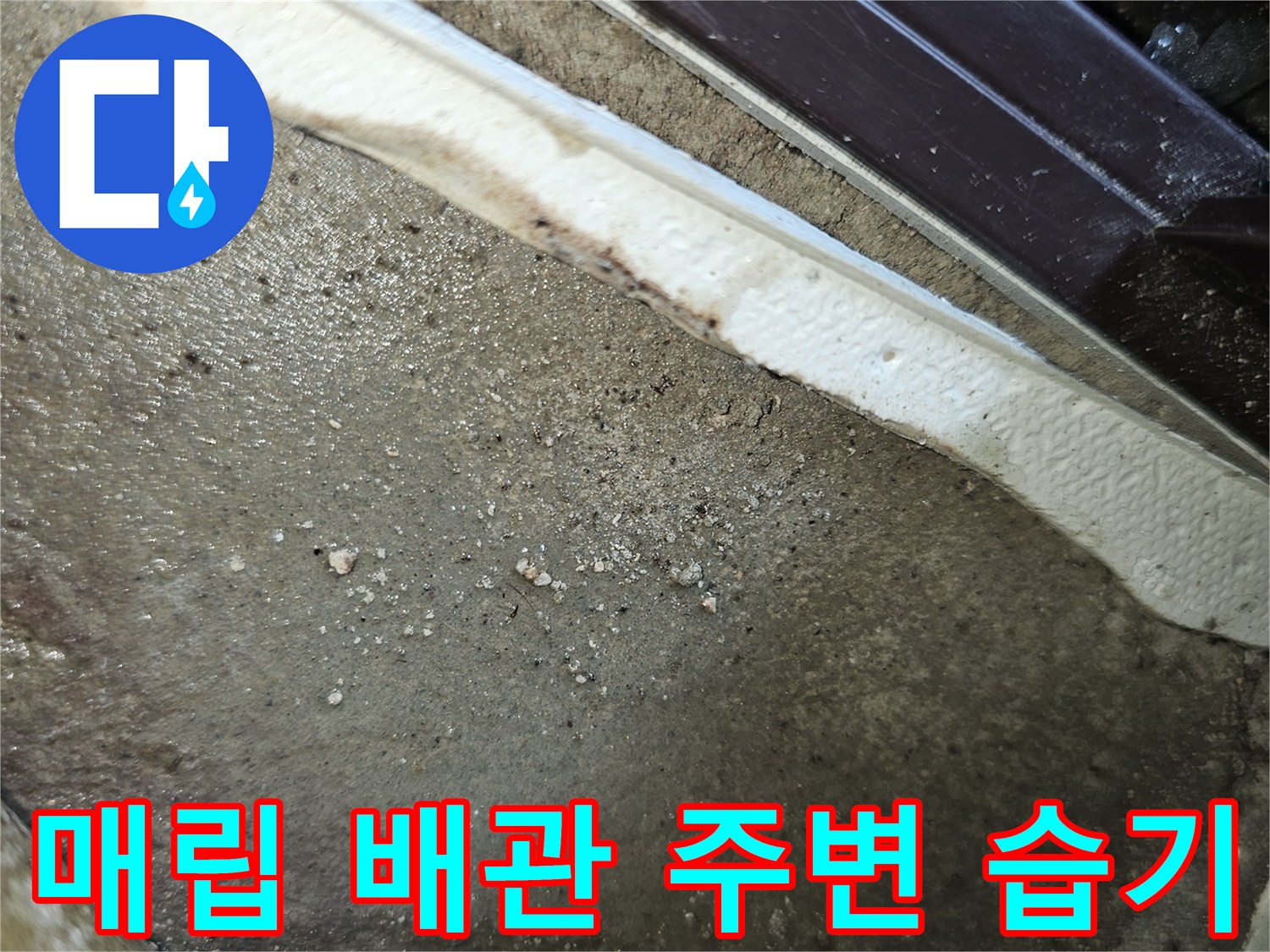 배관이 지나가는 통로 주변의 젖은 흙과 마감재 상태를 보여주는 사진입니다.